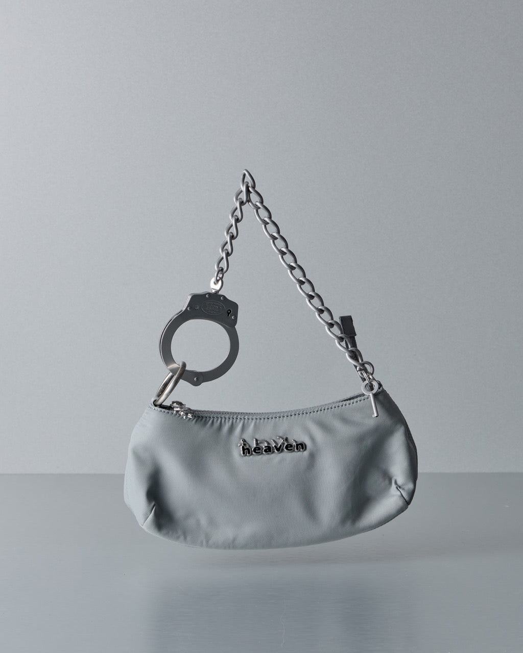 Silver Marc Jacobs handbag with chain strap and handcuff detail on a gray background