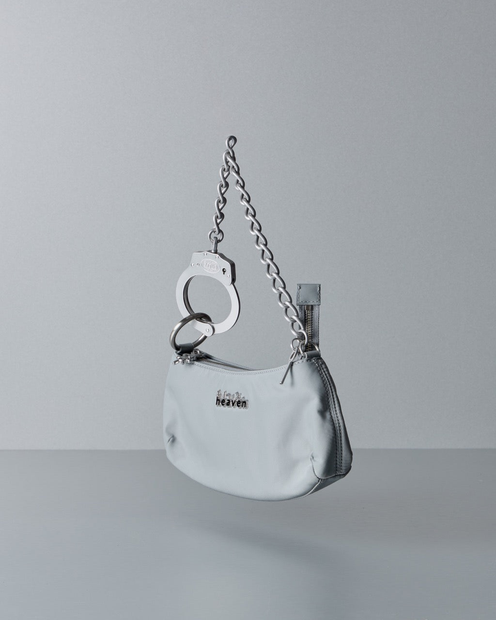 Silver Marc Jacobs handbag with chain strap and handcuff detail on a gray background