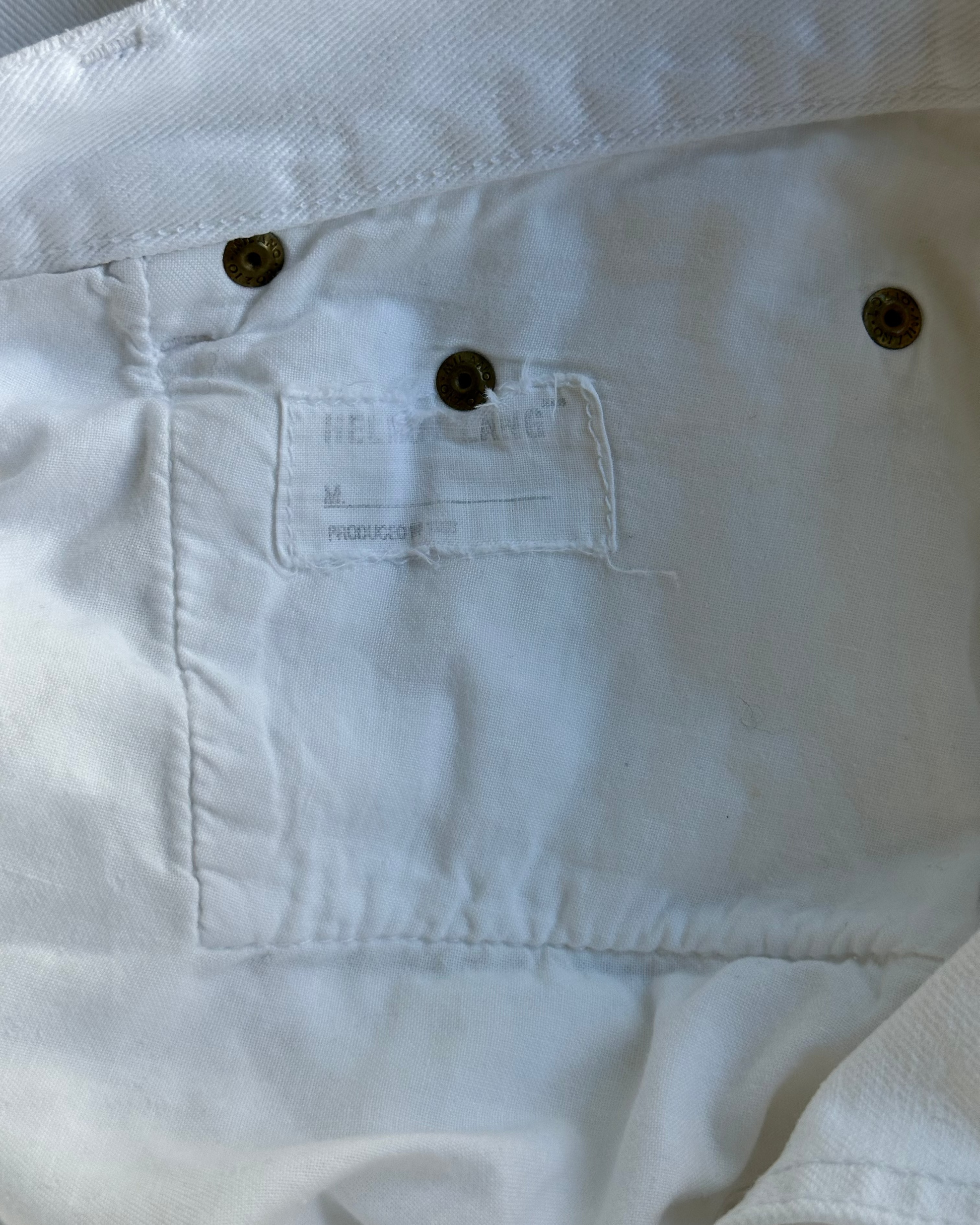 Close-up of a white pocket with a Helmut Lang brand label on a garment.