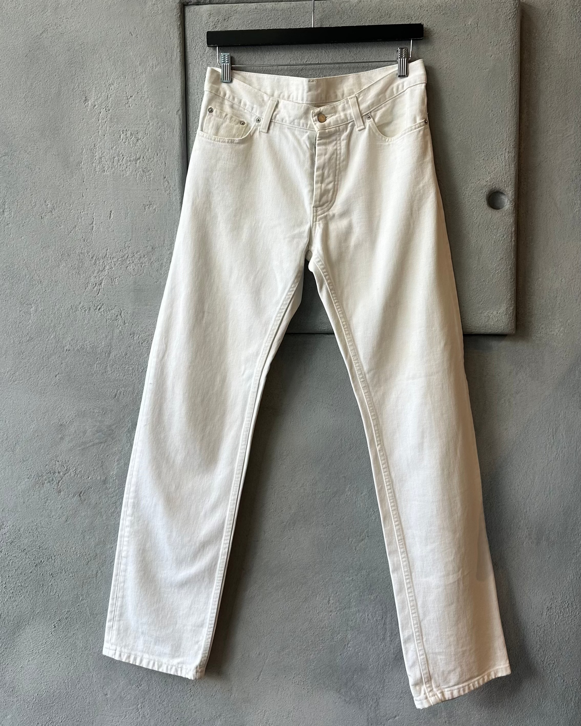 White Helmut Lang jeans hanging on a gray wall
