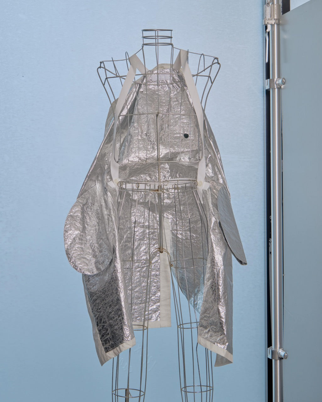Silver reflective inside of Helmut Lang jacket on a mannequin against a light blue background