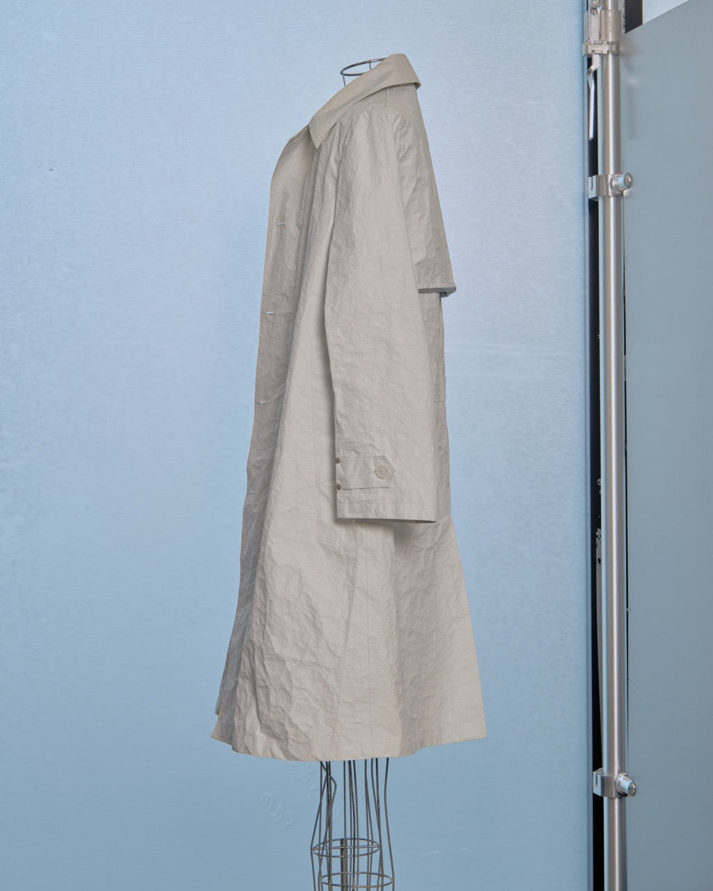 White Helmut Lang trench coat on a mannequin against a light blue background