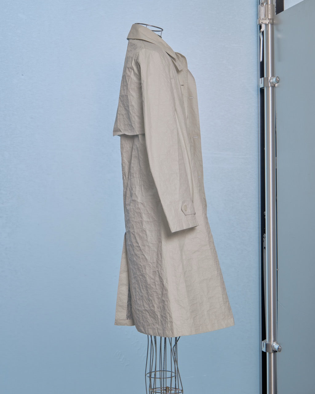 White Helmut Lang trench coat on a mannequin against a light blue wall