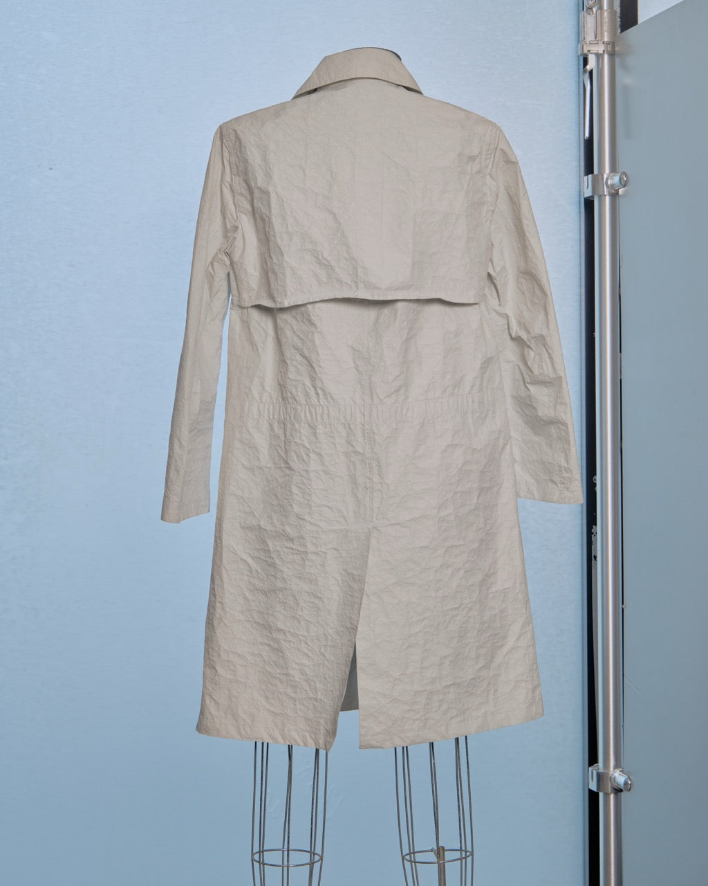 White Helmut Lang trench coat on a mannequin against a light blue background