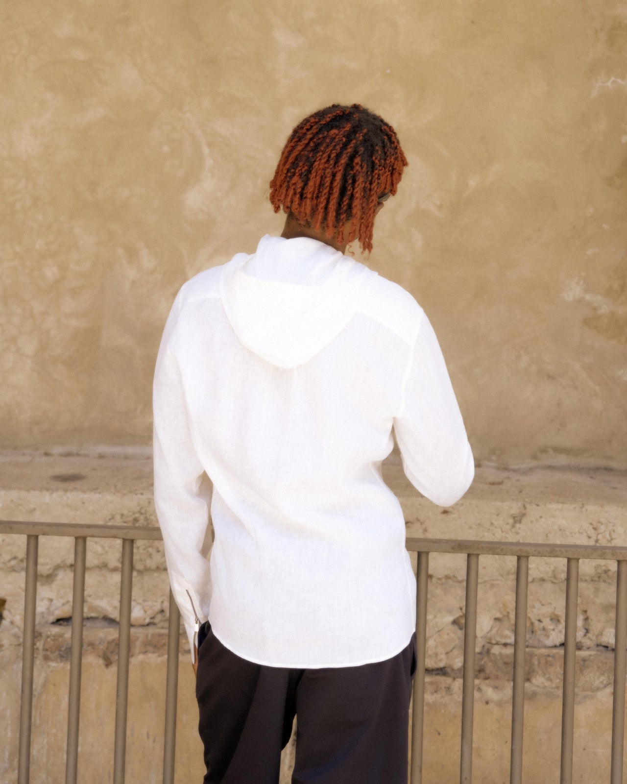 Young person in a white Hermès hoodie and black shorts stands confidently, wearing sunglasses. 