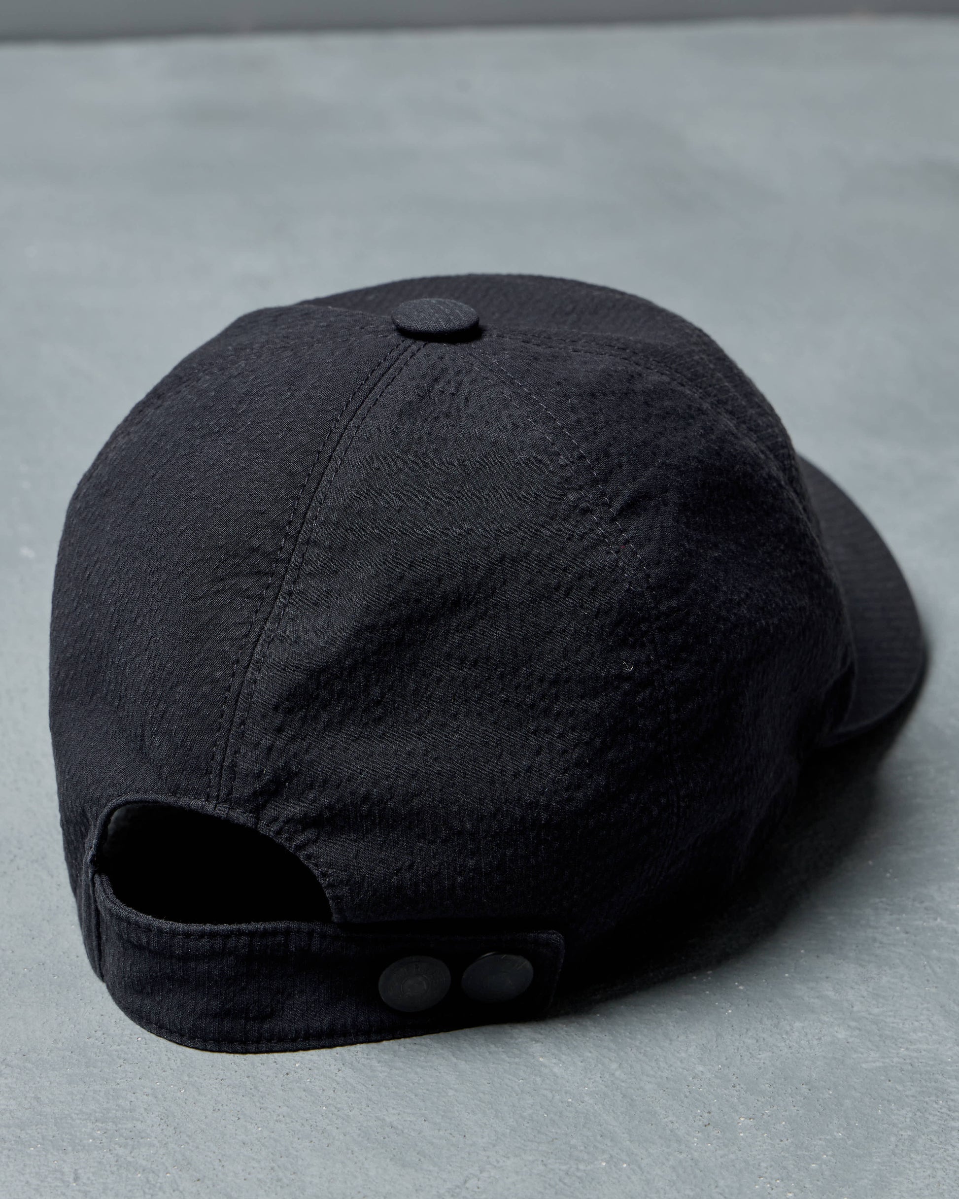 Black Hermes cap on a gray surface