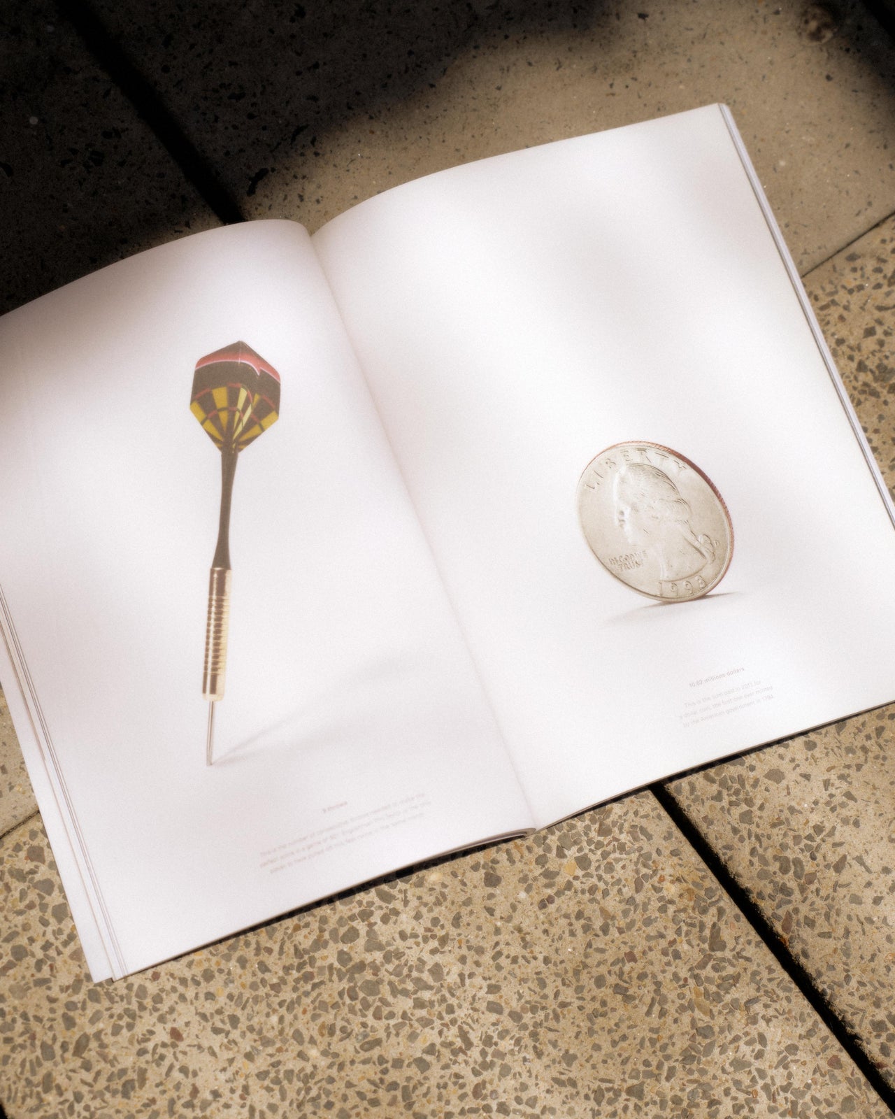 A softcover Hermes magazine with a die on the cover, placed on a textured surface.