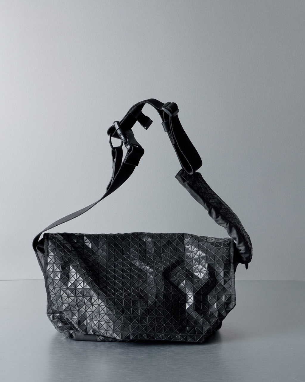Black geometric Issey Miyake BaoBao patterned bag on a gray background