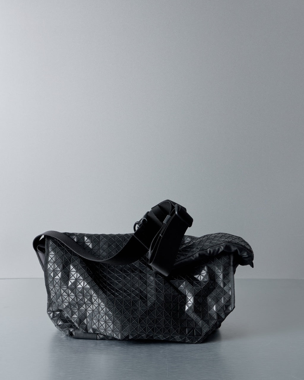 Black quilted Issey Miyake Bao Bao handbag on a gray background