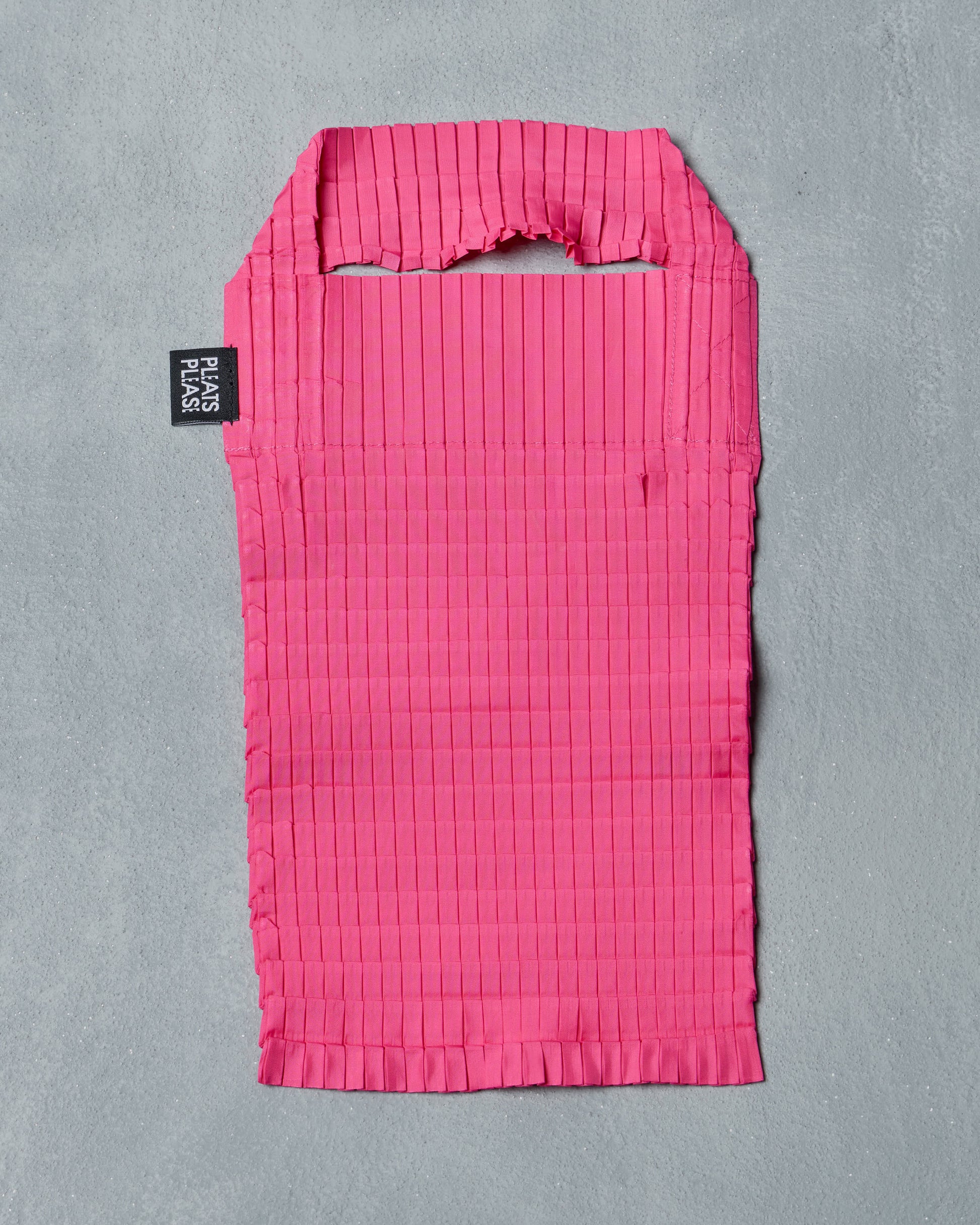 Pink pleated Issey Miyake bag with a brand label on a gray background