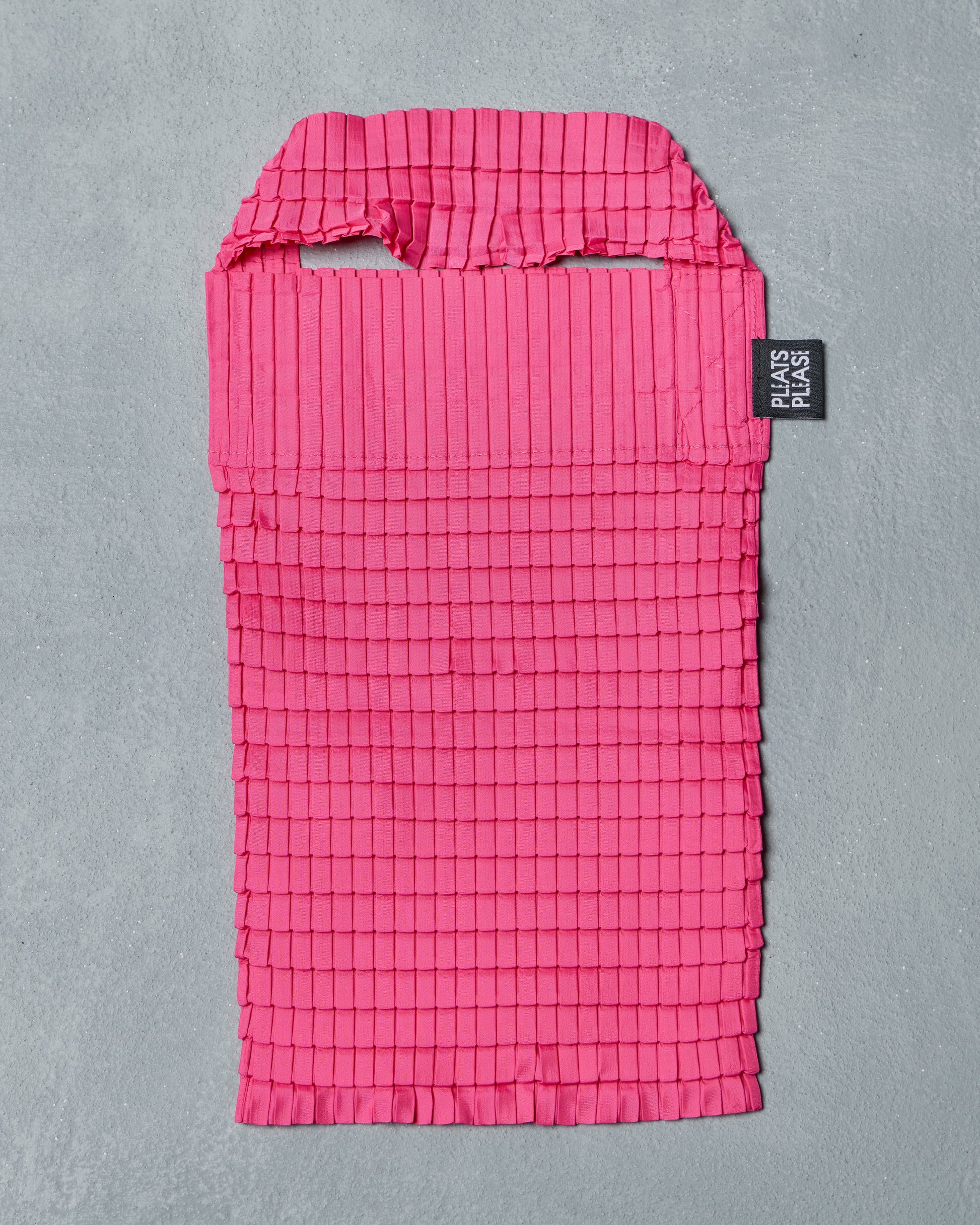 Pink grid-patterned Issey Miyake bag with a black label on a gray background