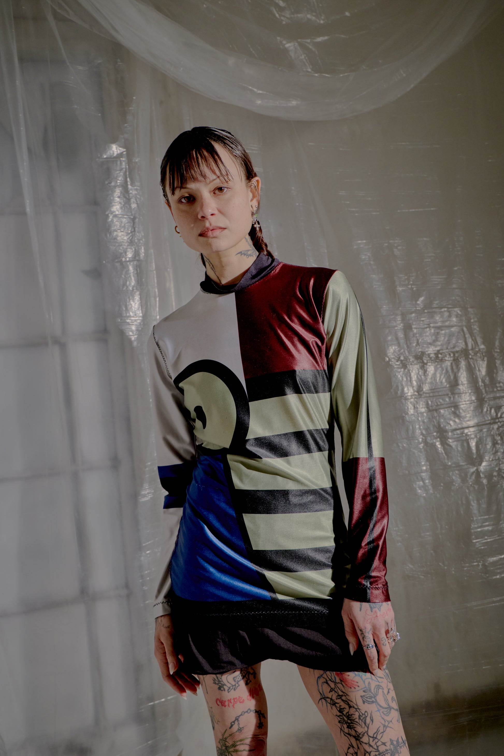 Person wearing a colourful long-sleeve  Jean Paul Gaultier shirt with geometric patterns in a minimalistic setting.