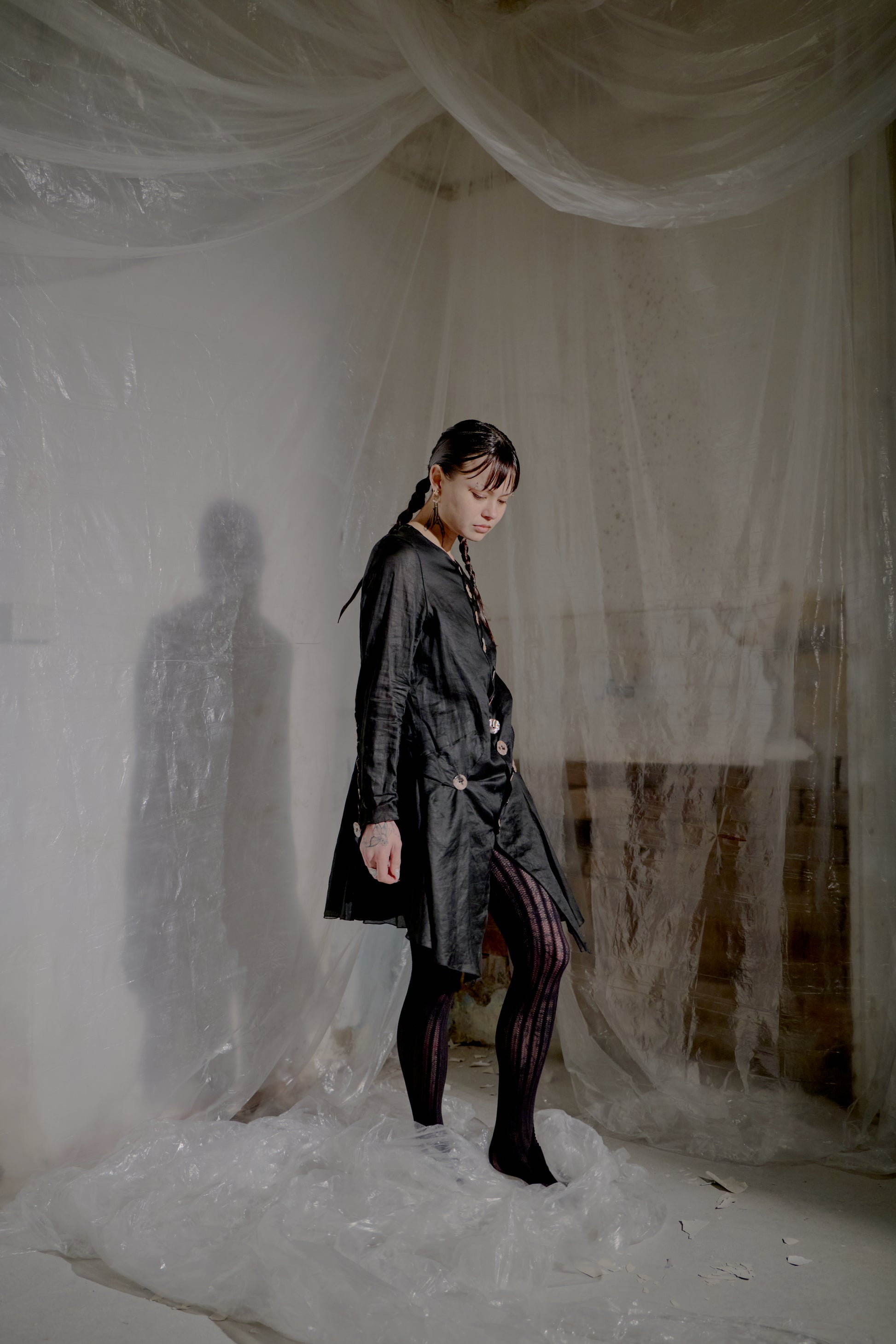Person wearing a Jean Paul Gaultier jacket and standing in a room with white plastic sheeting draped over the walls and floor