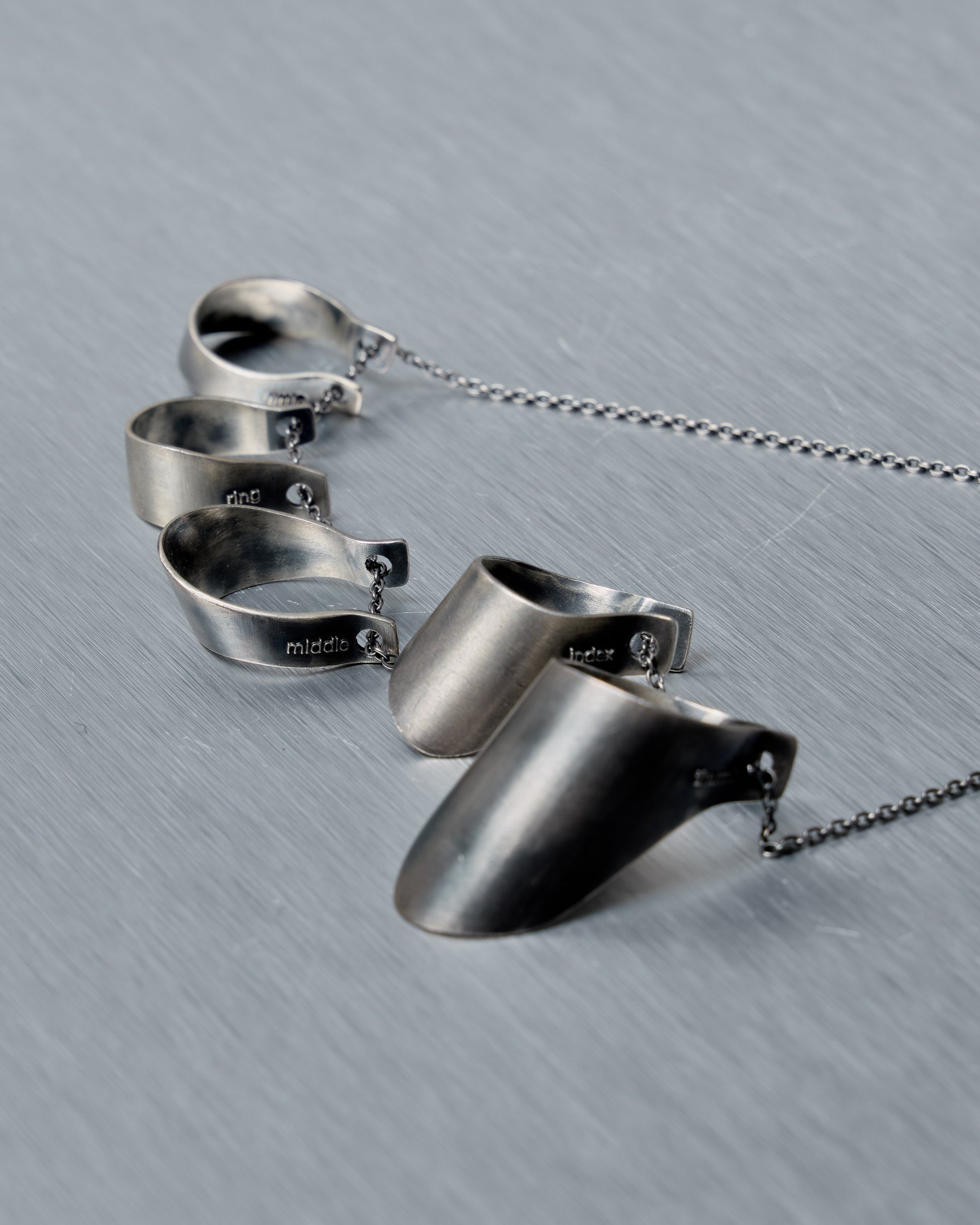 Set of silver rings and a pendant from Julius on a gray surface