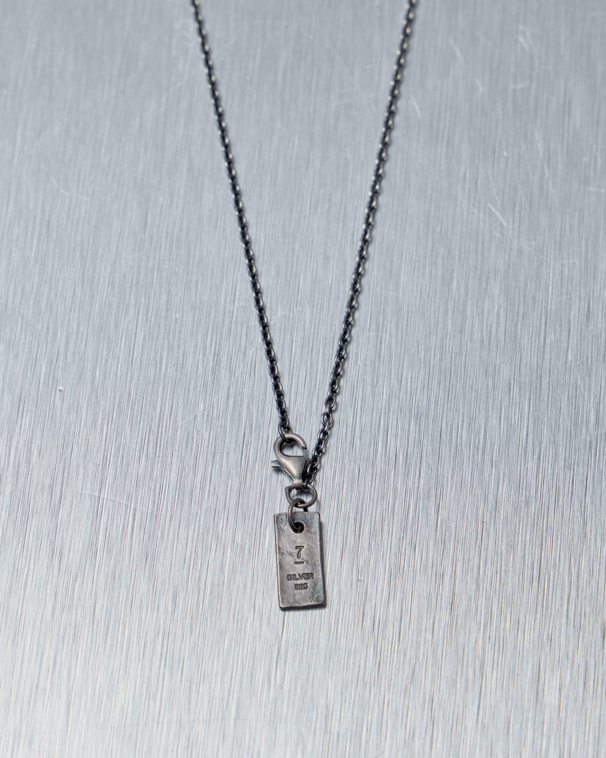 Silver necklace from Julius with a rectangular pendant on a gray background