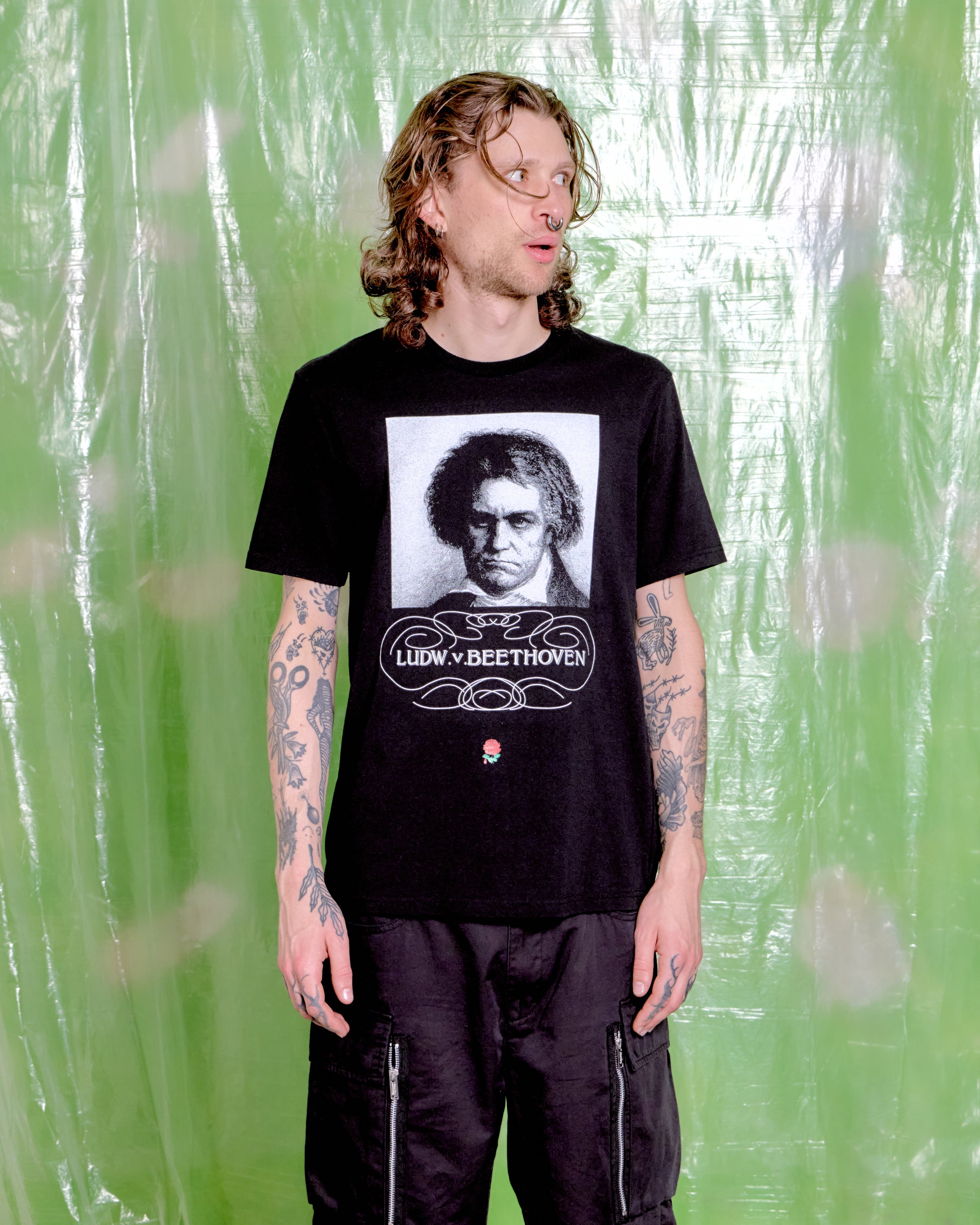 Person wearing a black t-shirt with a graphic of Ludwig van Beethoven against a green textured background