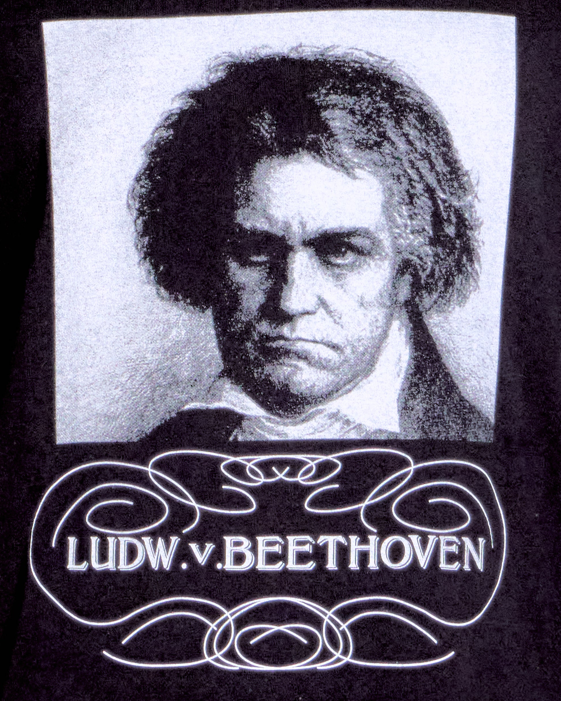 Black and white portrait of a famous composer with decorative text below on a black background