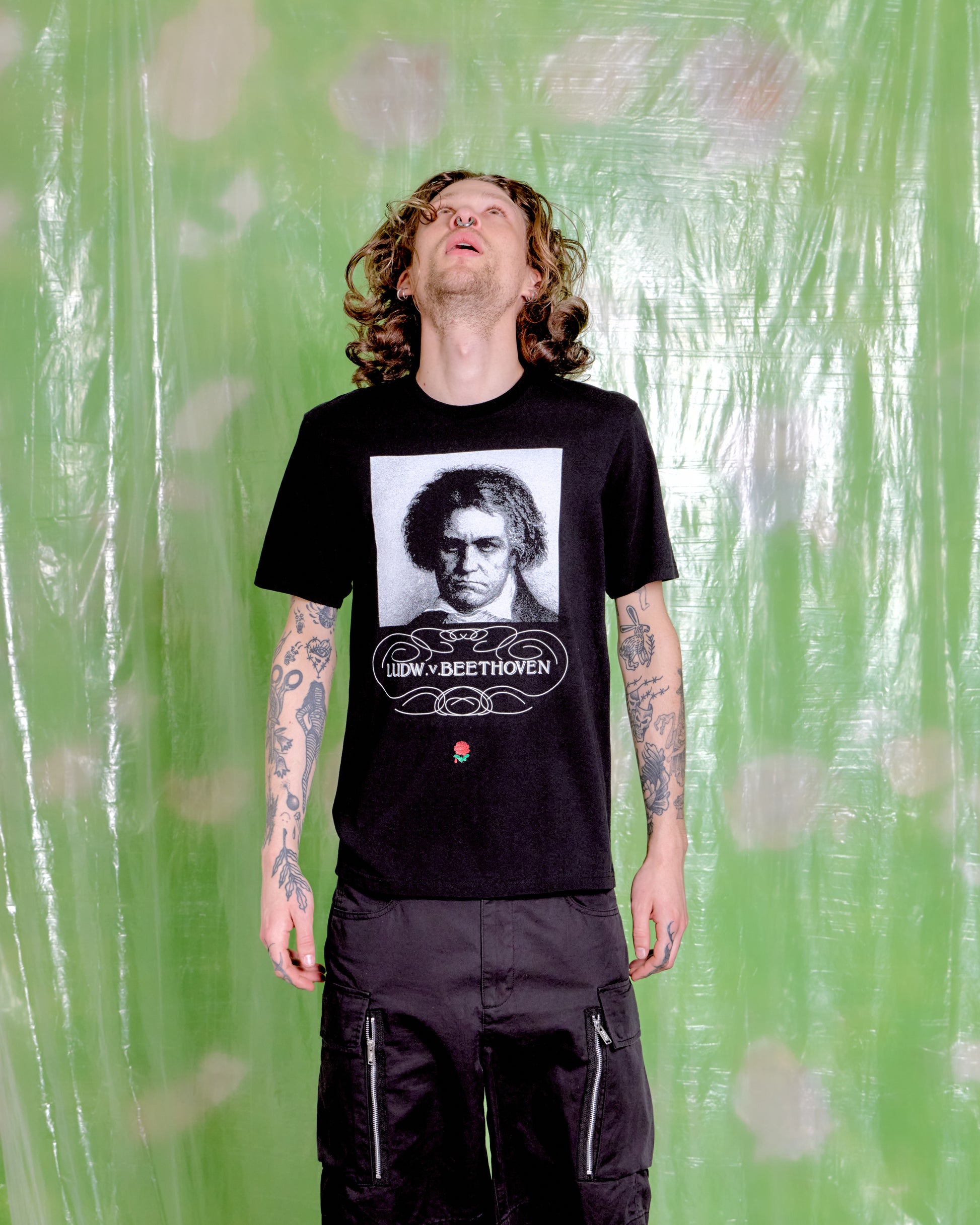 Person wearing a black t-shirt with a graphic design against a green patterned background