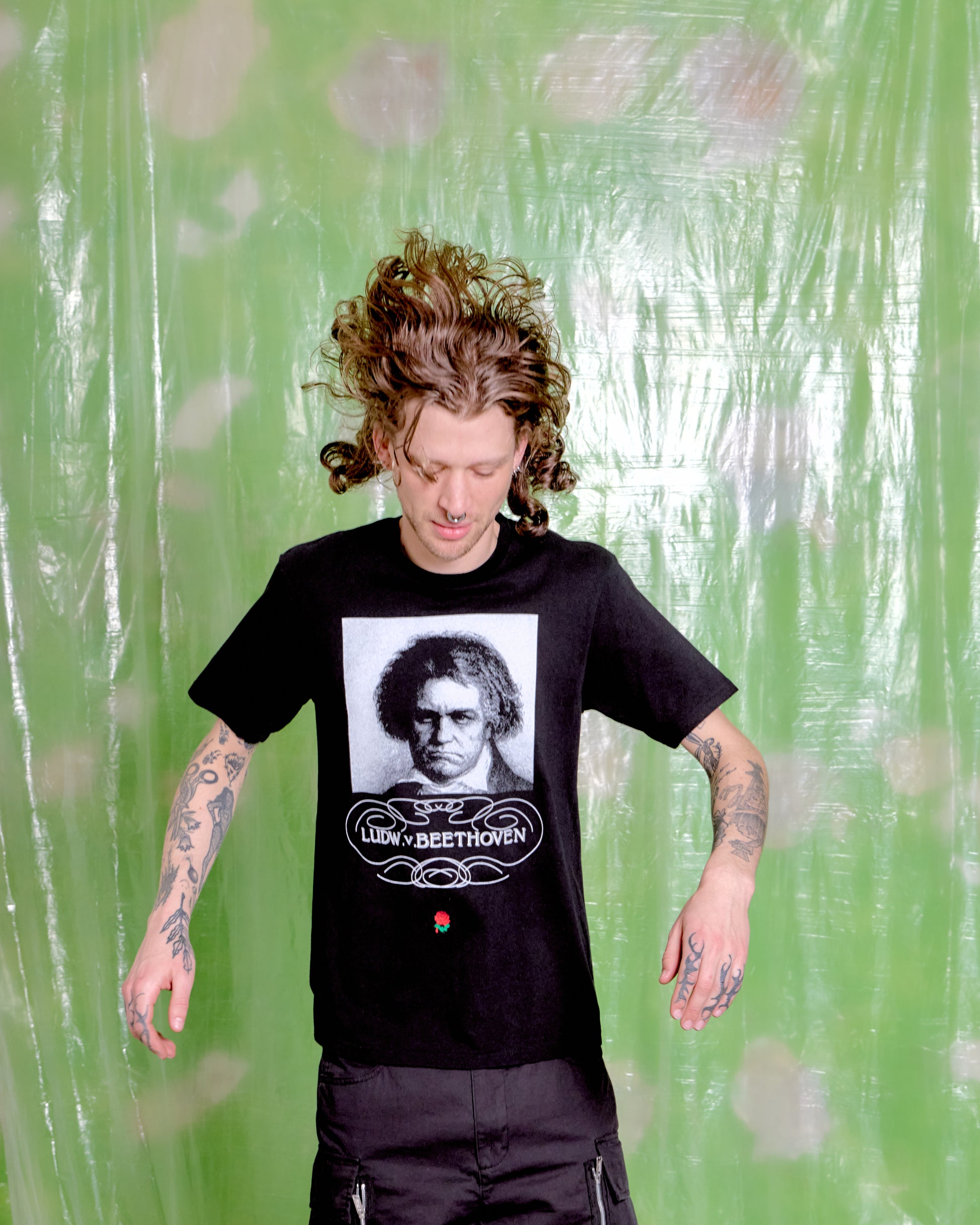 Person wearing a black t-shirt with a graphic design on a green textured background