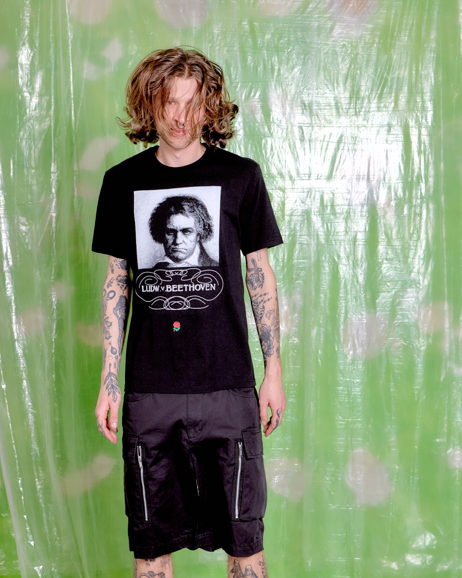 Person wearing a black t-shirt with a graphic design against a green patterned background