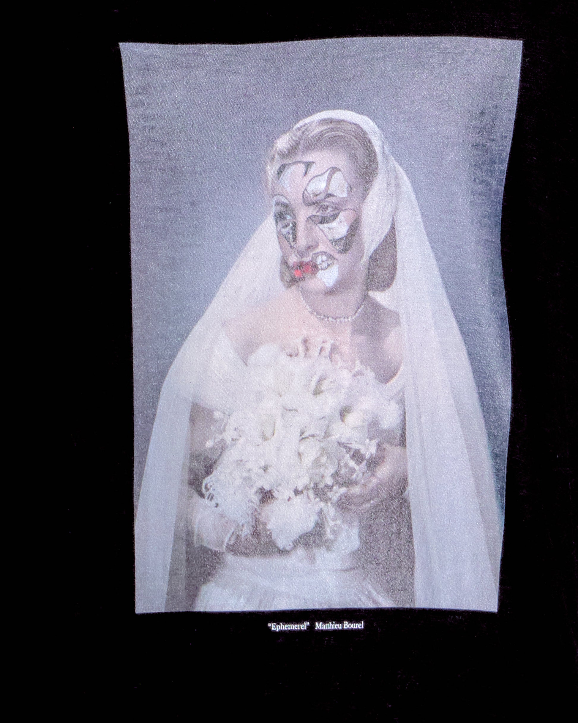 Person in a wedding dress with a veil holding flowers on a black background