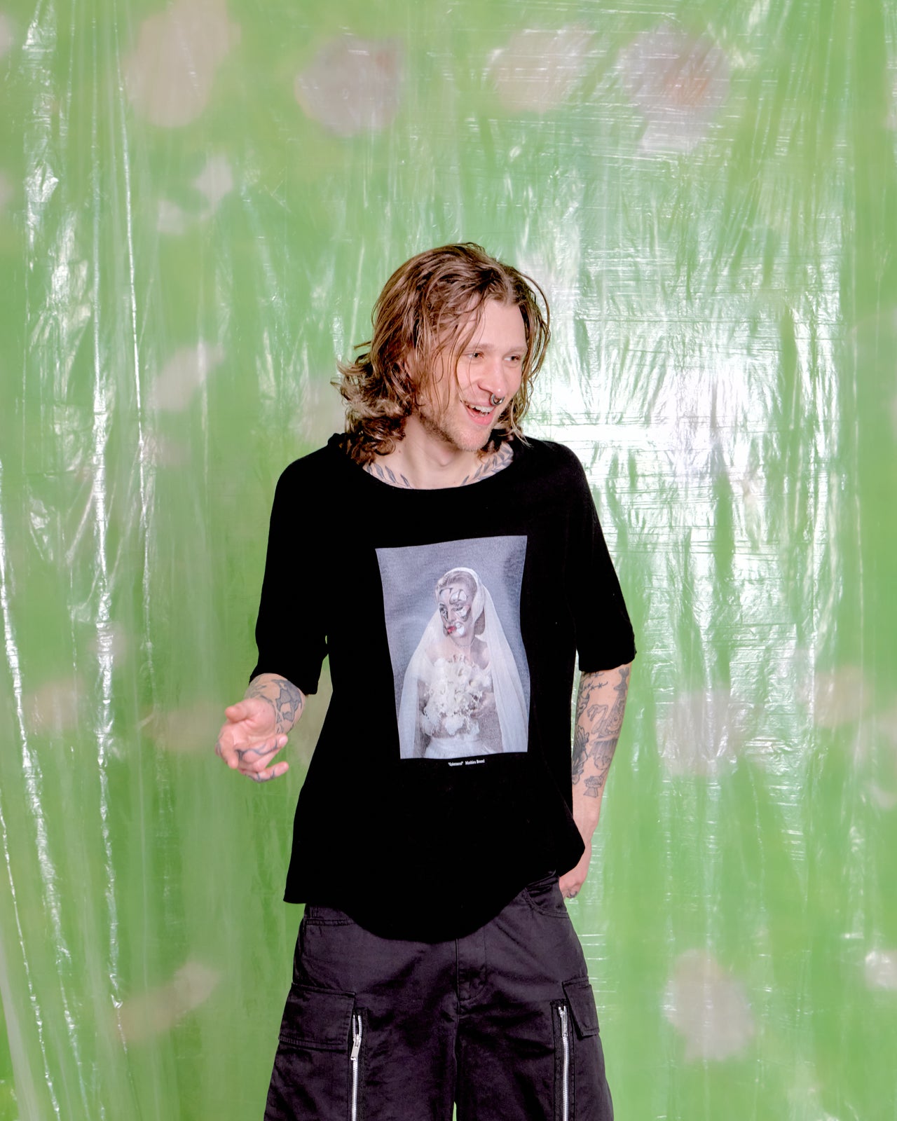 Person wearing a black t-shirt with a graphic design against a green patterned background