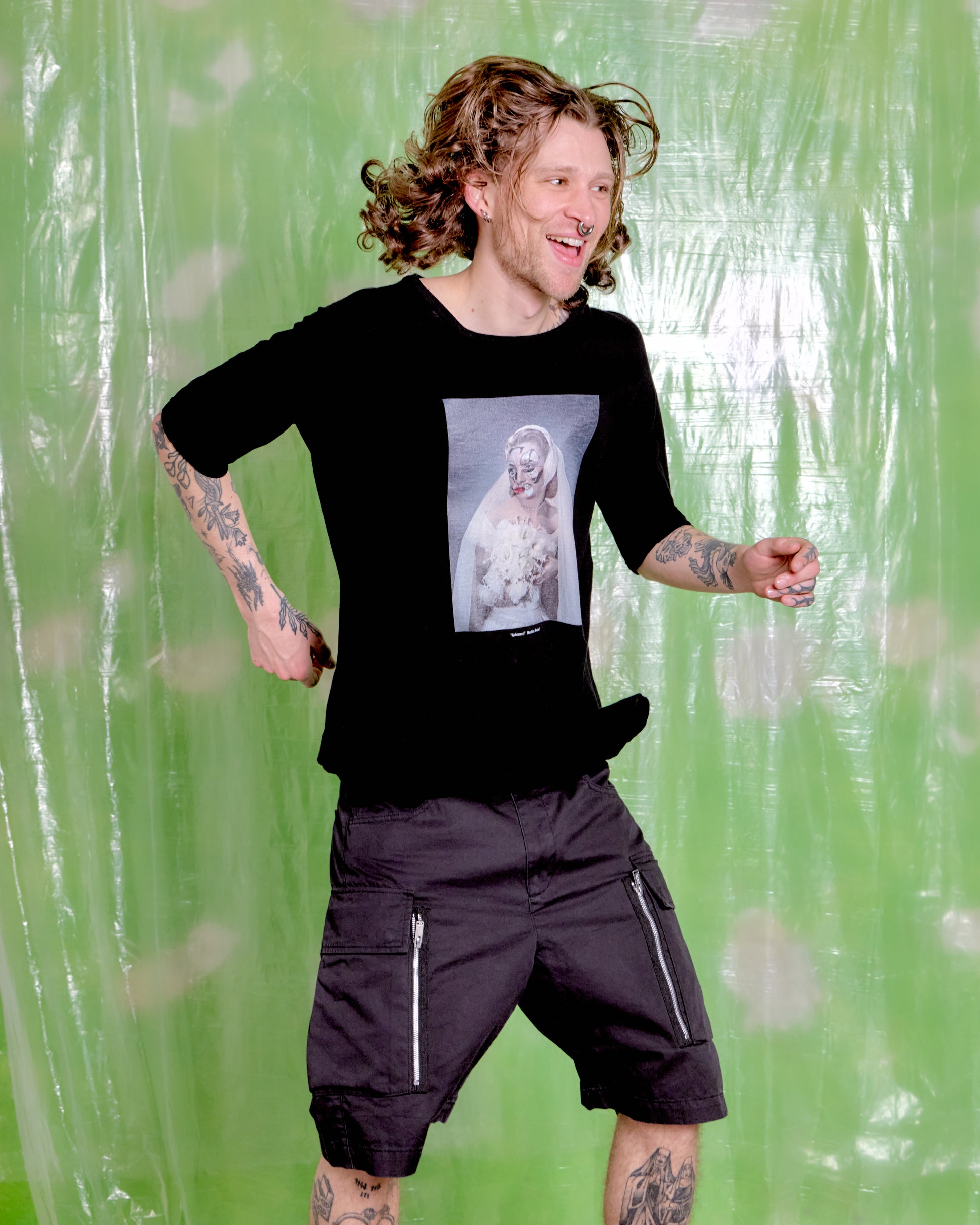 Person wearing a black t-shirt with a graphic design against a green patterned background