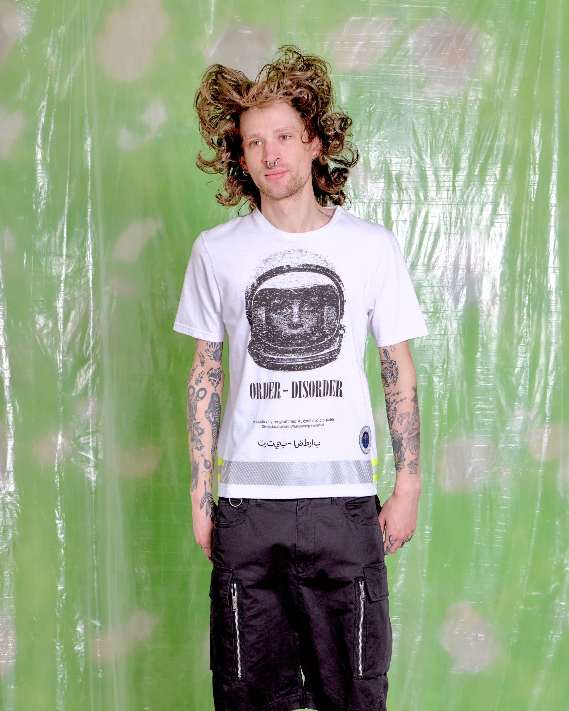 Person wearing a white t-shirt with a graphic design on a green background