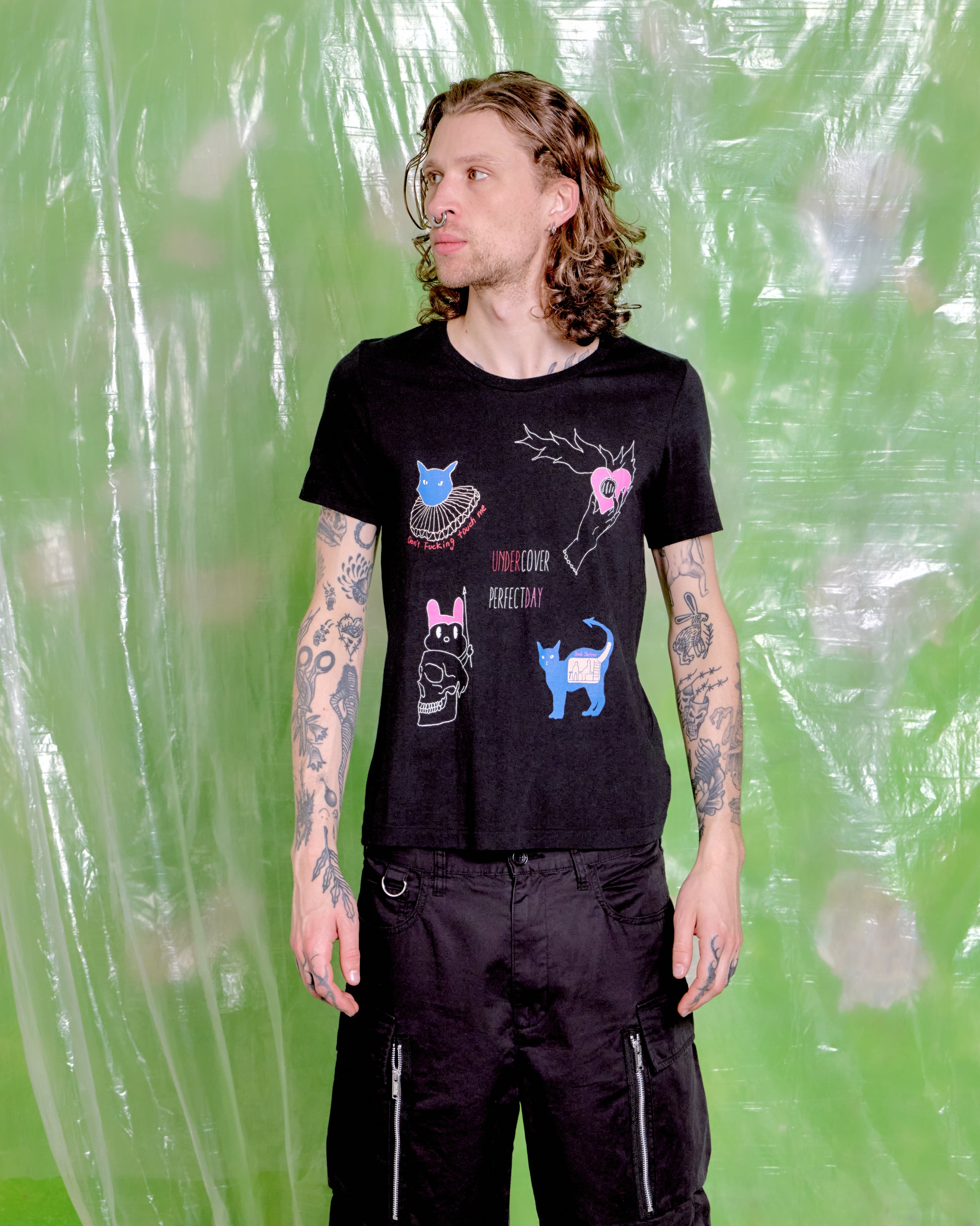 Person wearing a black t-shirt with graphic designs against a green background