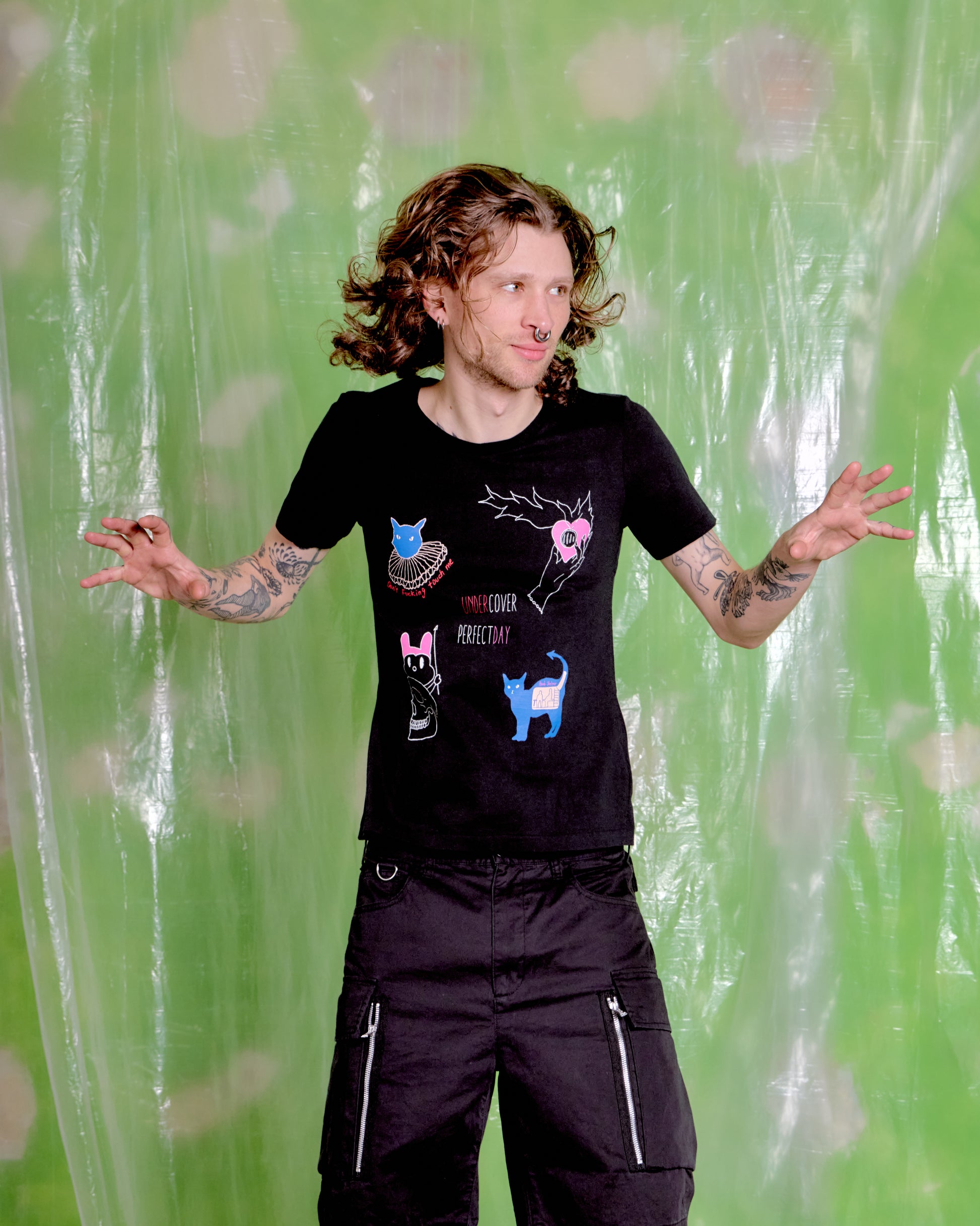 Person wearing a black t-shirt with colorful graphics against a green patterned background