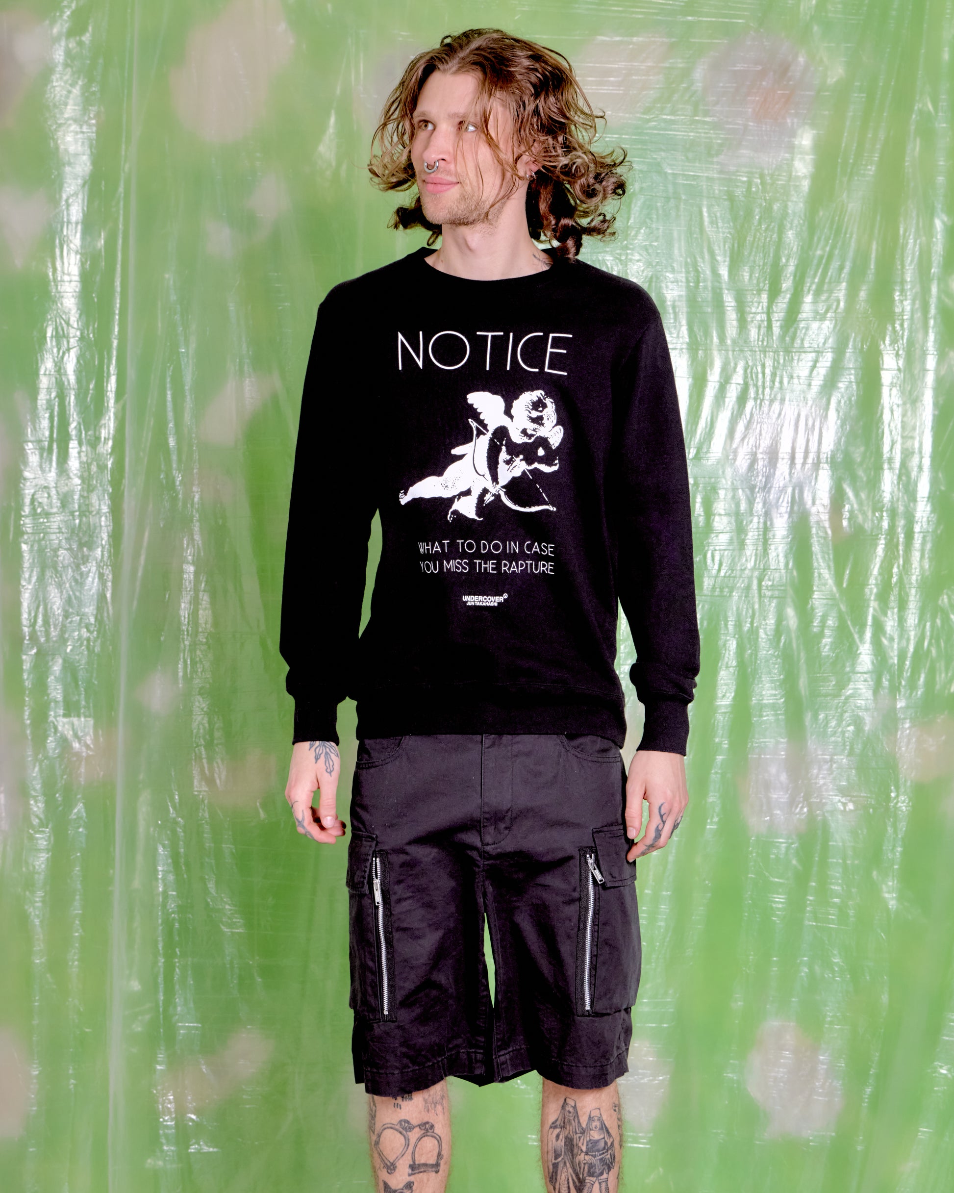 Person wearing a black sweatshirt with graphic design and text against a green background