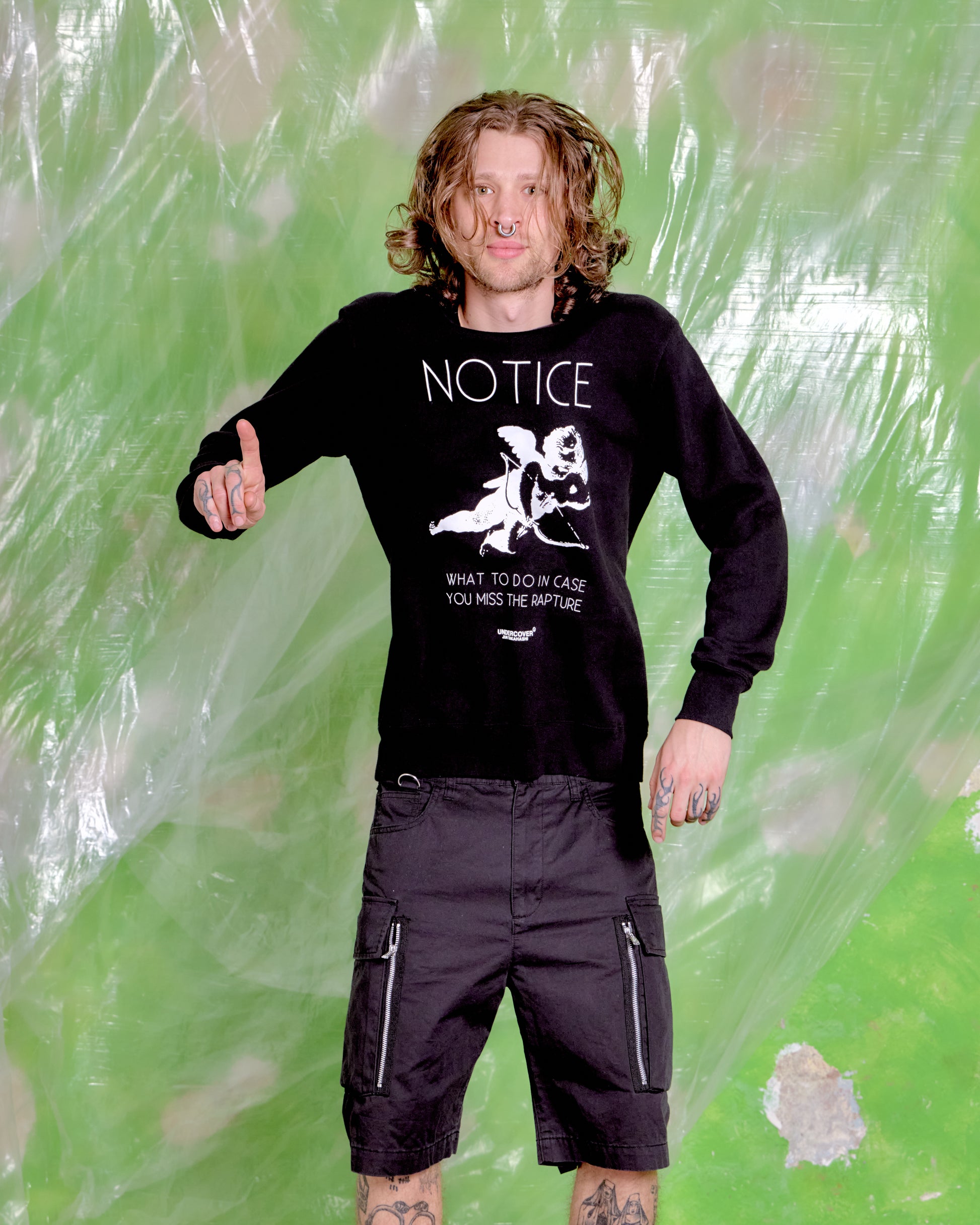 Person wearing a black sweatshirt with text and graphics against a green textured background