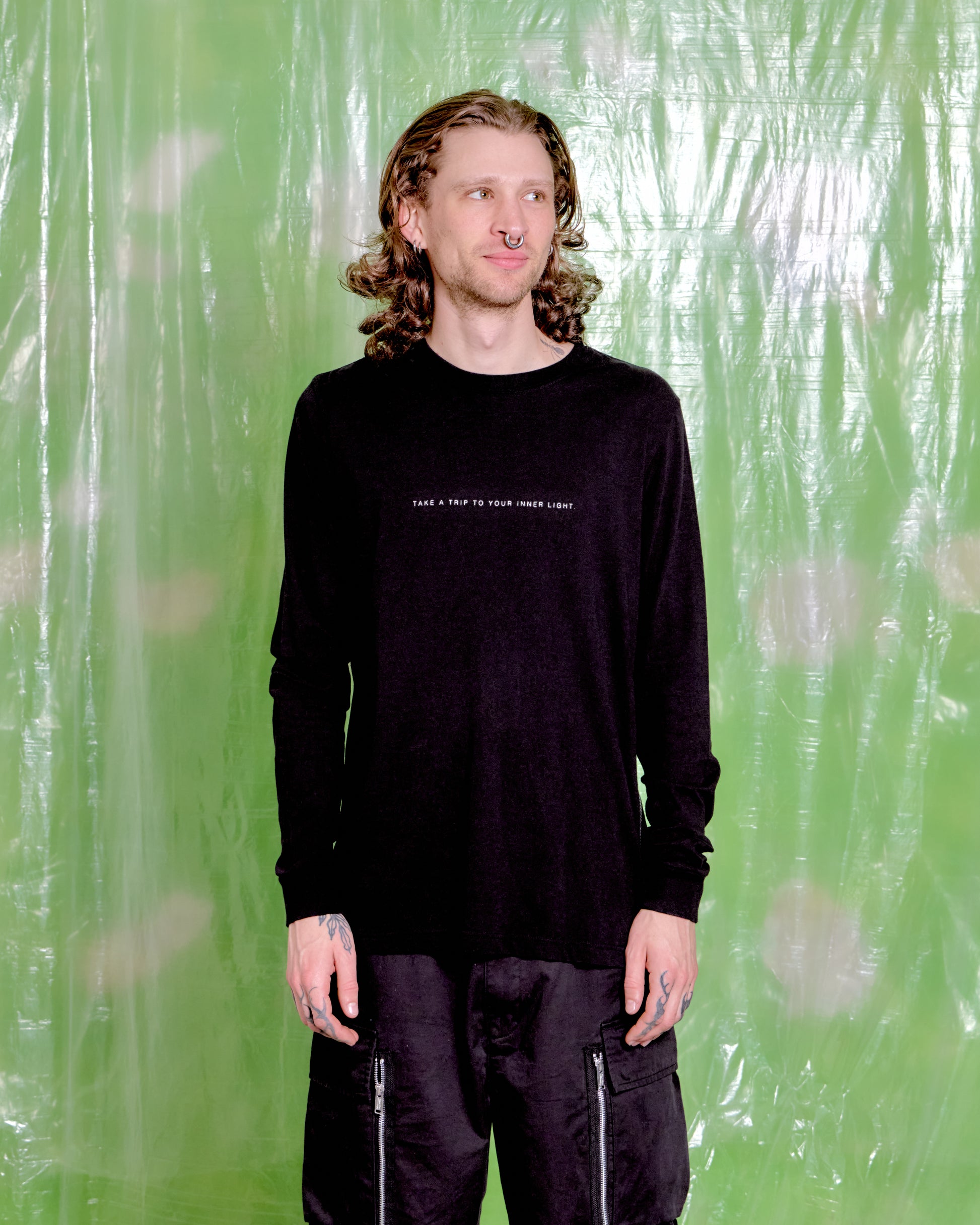 Person wearing a black long-sleeve shirt with text against a green background
