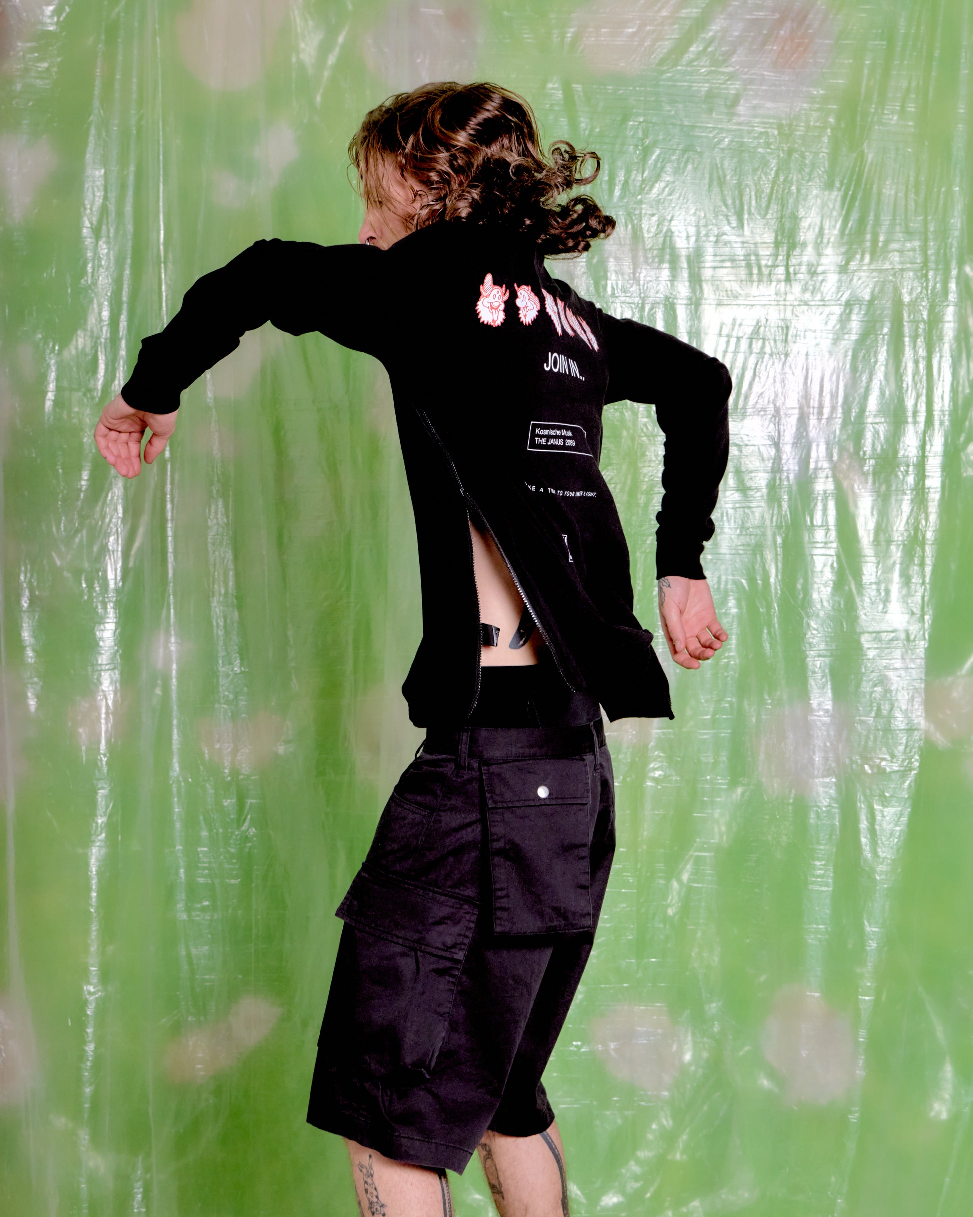 Person wearing a black jacket with visible branding against a green patterned background
