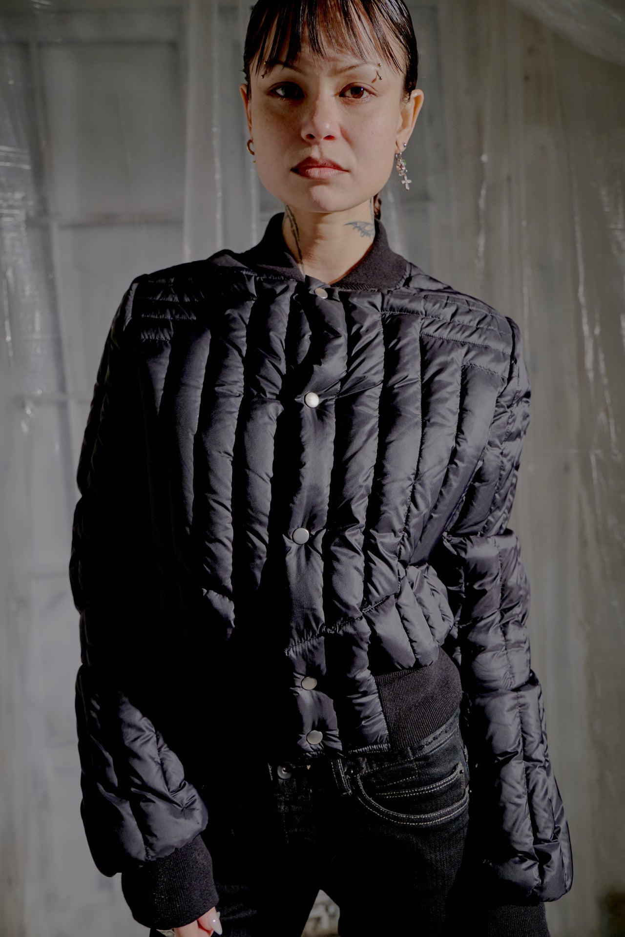 Person wearing a black quilted Rick Owens jacket in a dimly lit room.