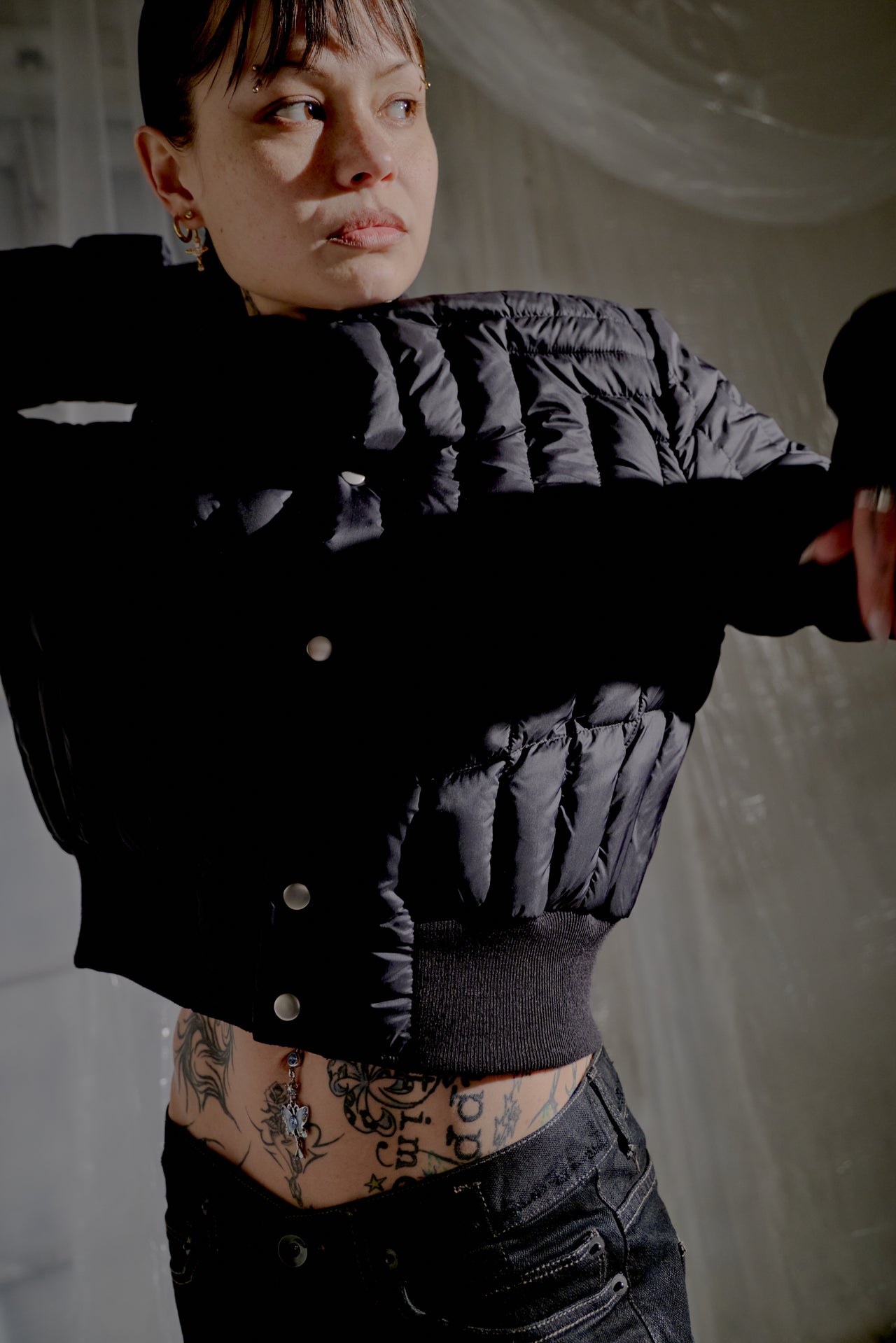 Person wearing a black quilted Rick Owens jacket in a dimly lit room.