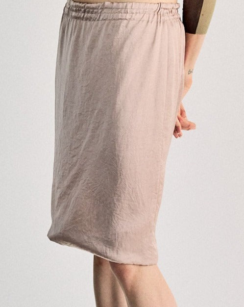 A woman standing wearing a Lanvin silk skirt with a ruched elastic waistband, in a beige color, with a visible brand mark on the skirt.