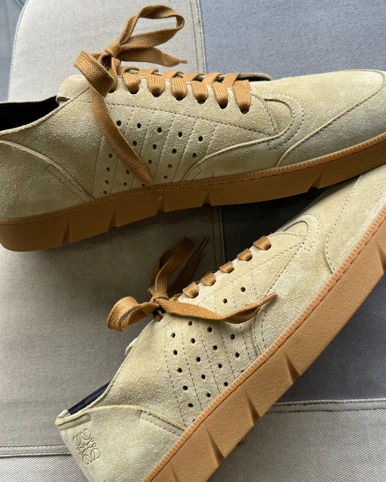 Beige Loewe sneaker with brown sole on a gray surface against a gray background