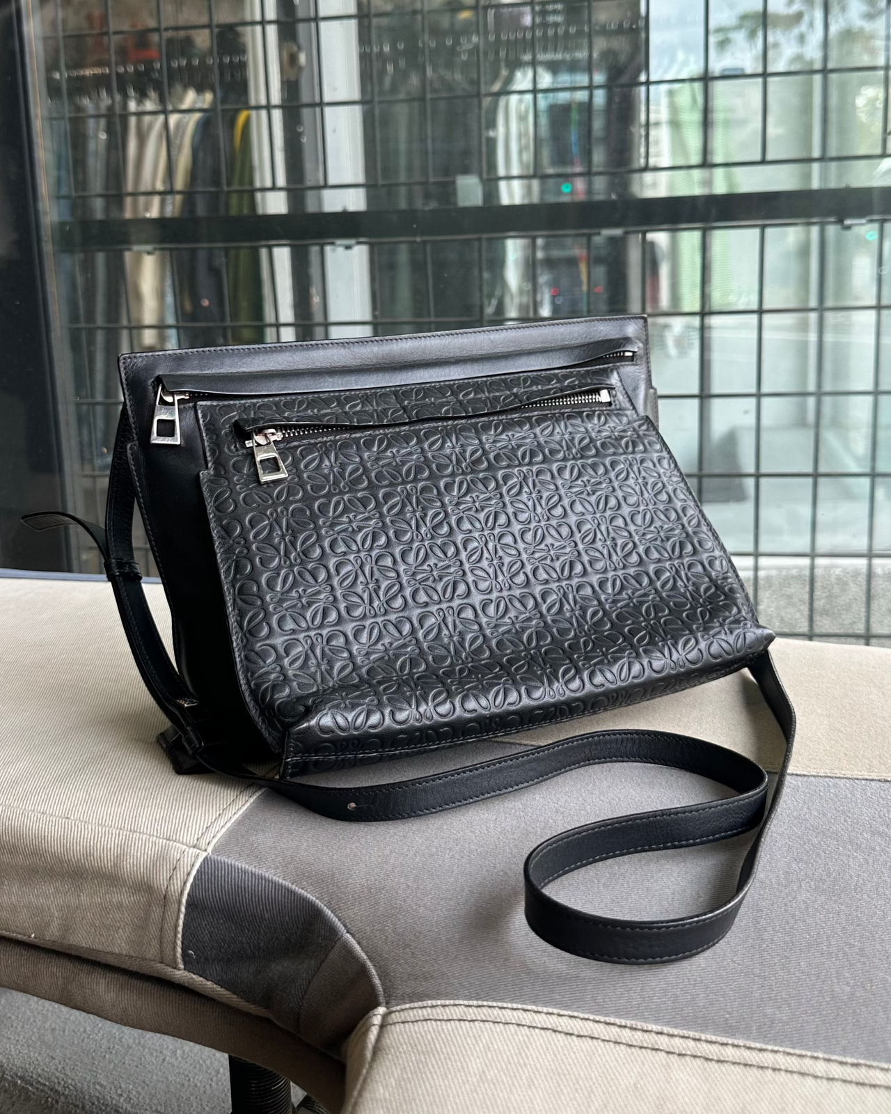 Black textured Loewe handbag on a chair with a blurred background