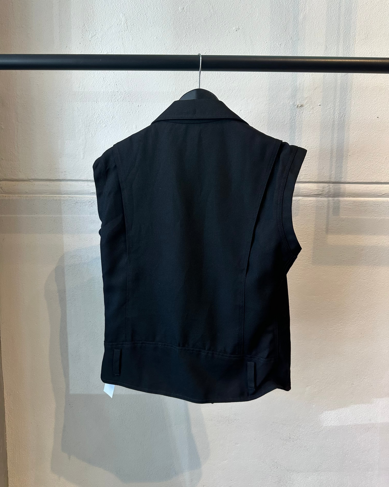 Black Loewe vest with zippers on a hanger against a neutral background