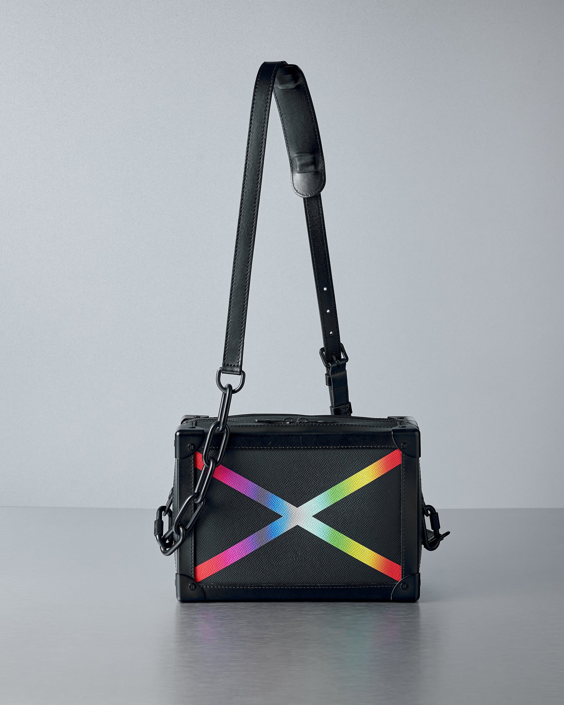 Black Louis Vuitton handbag with a rainbow 'X' design on a gray background