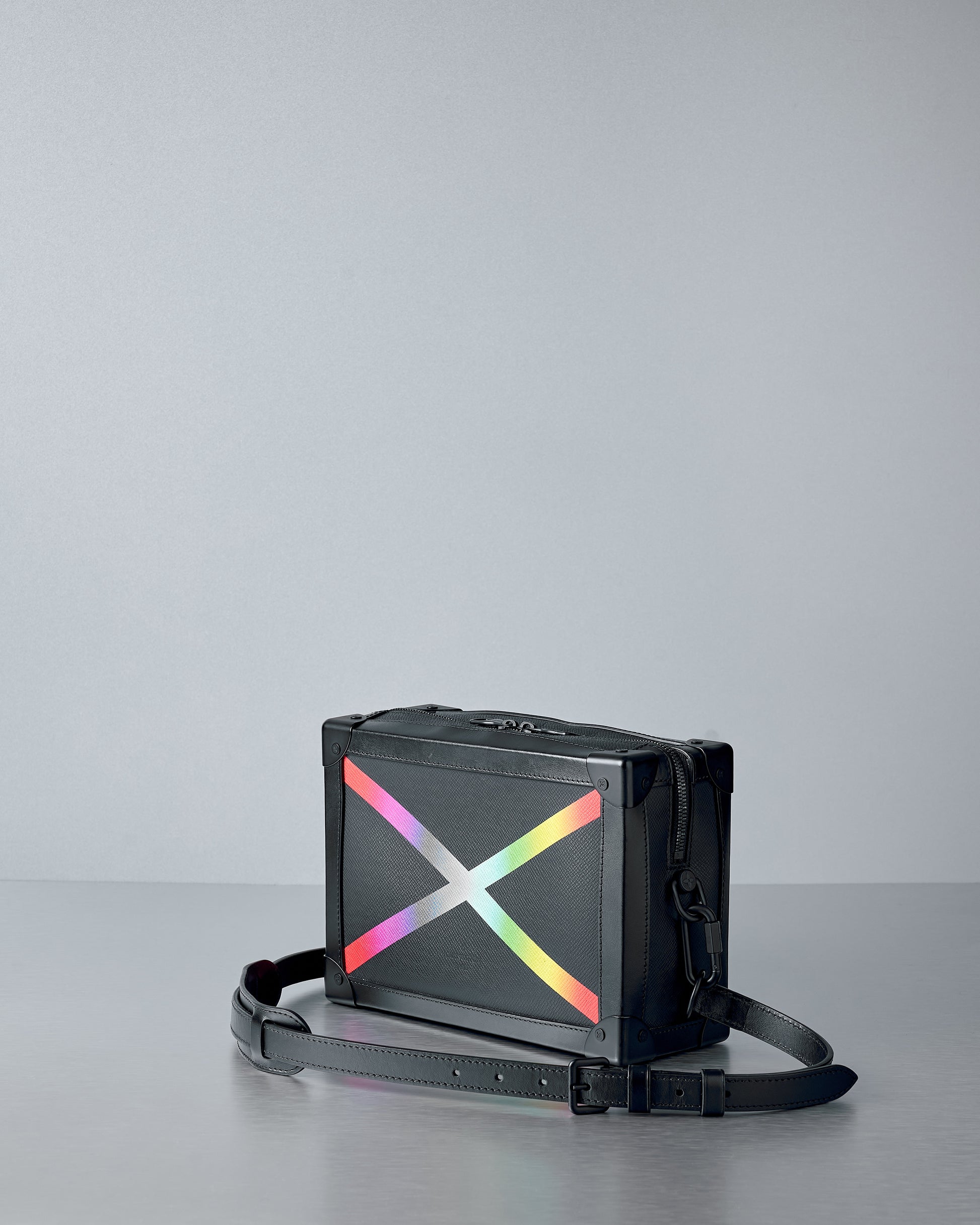 Black Louis Vuitton bag with a colourful 'X' design on a gray background