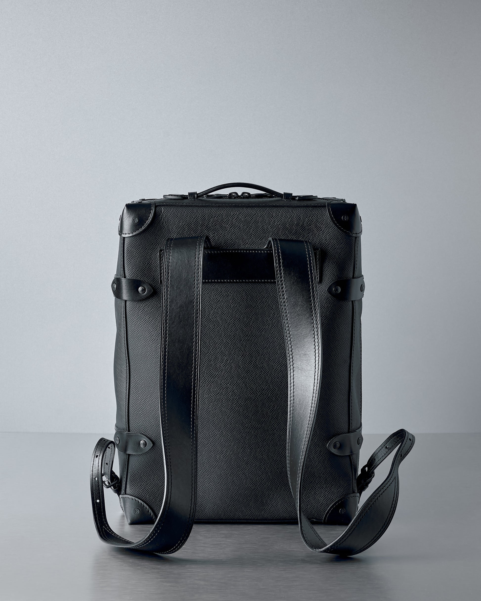 Black Louis Vuitton Taiga leather backpack on a grey background