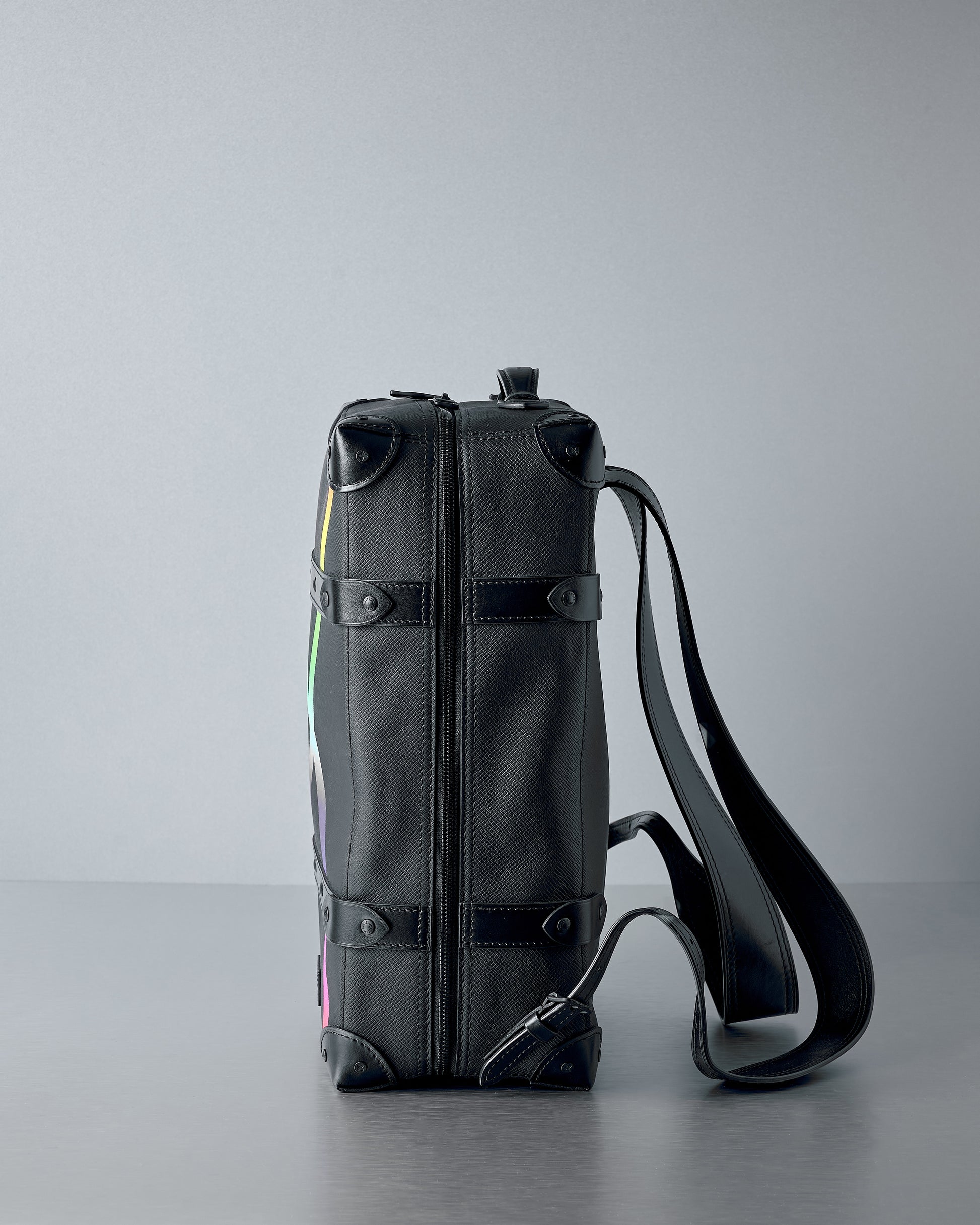 Black Louis Vuitton backpack with a colourful design on a grey background