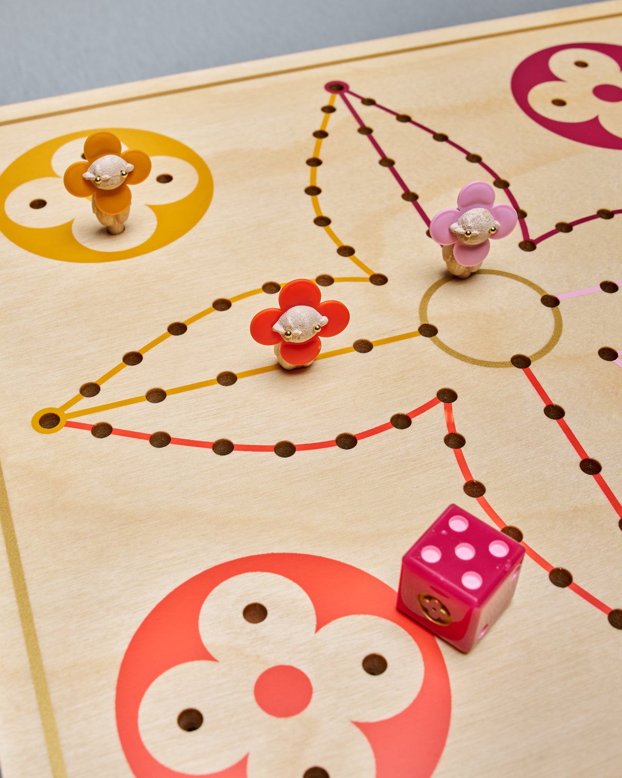 Louis Vuitton game board with colorful markers and a die on a wooden surface