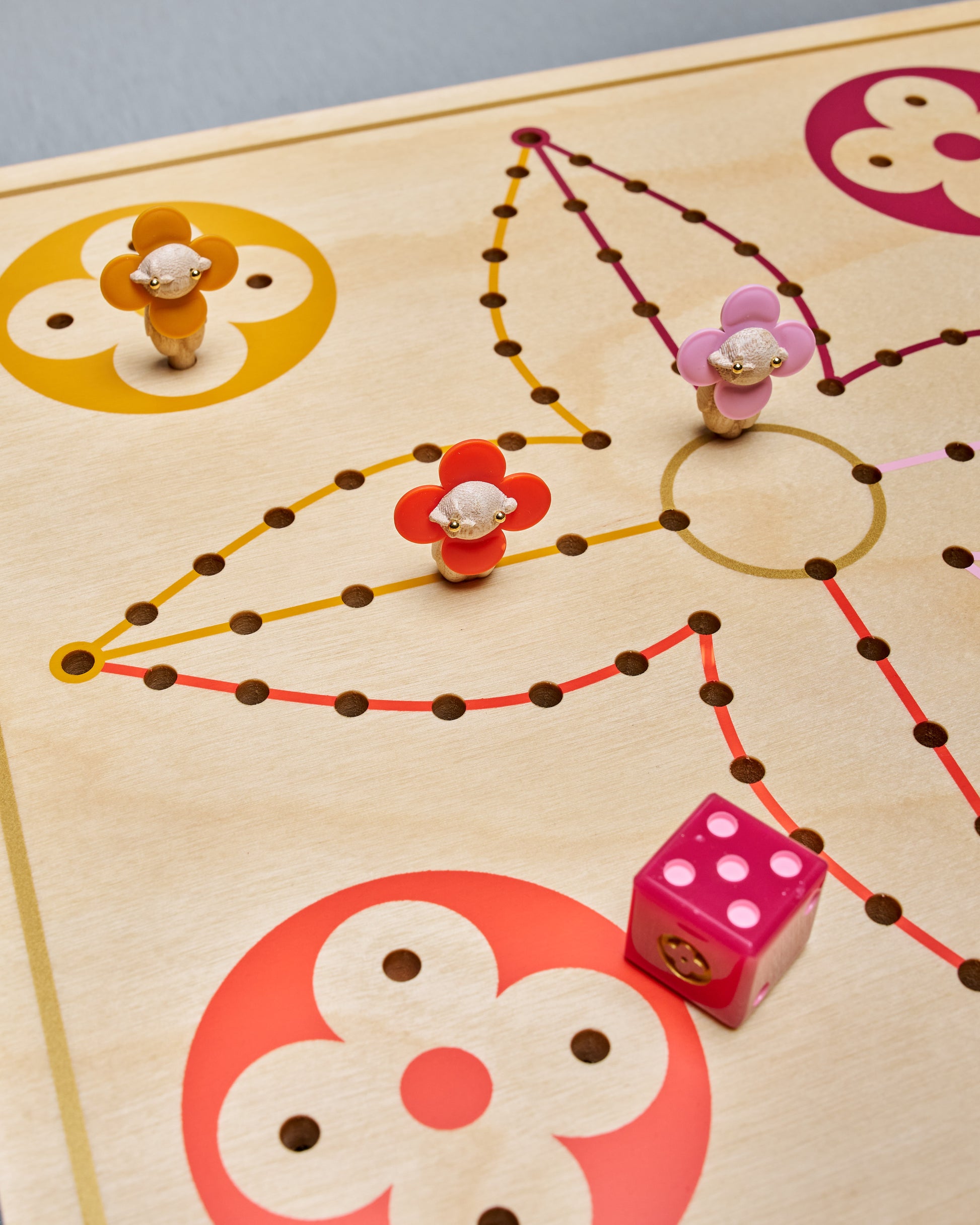 Louis Vuitton game board with colorful markers and a die on a wooden surface
