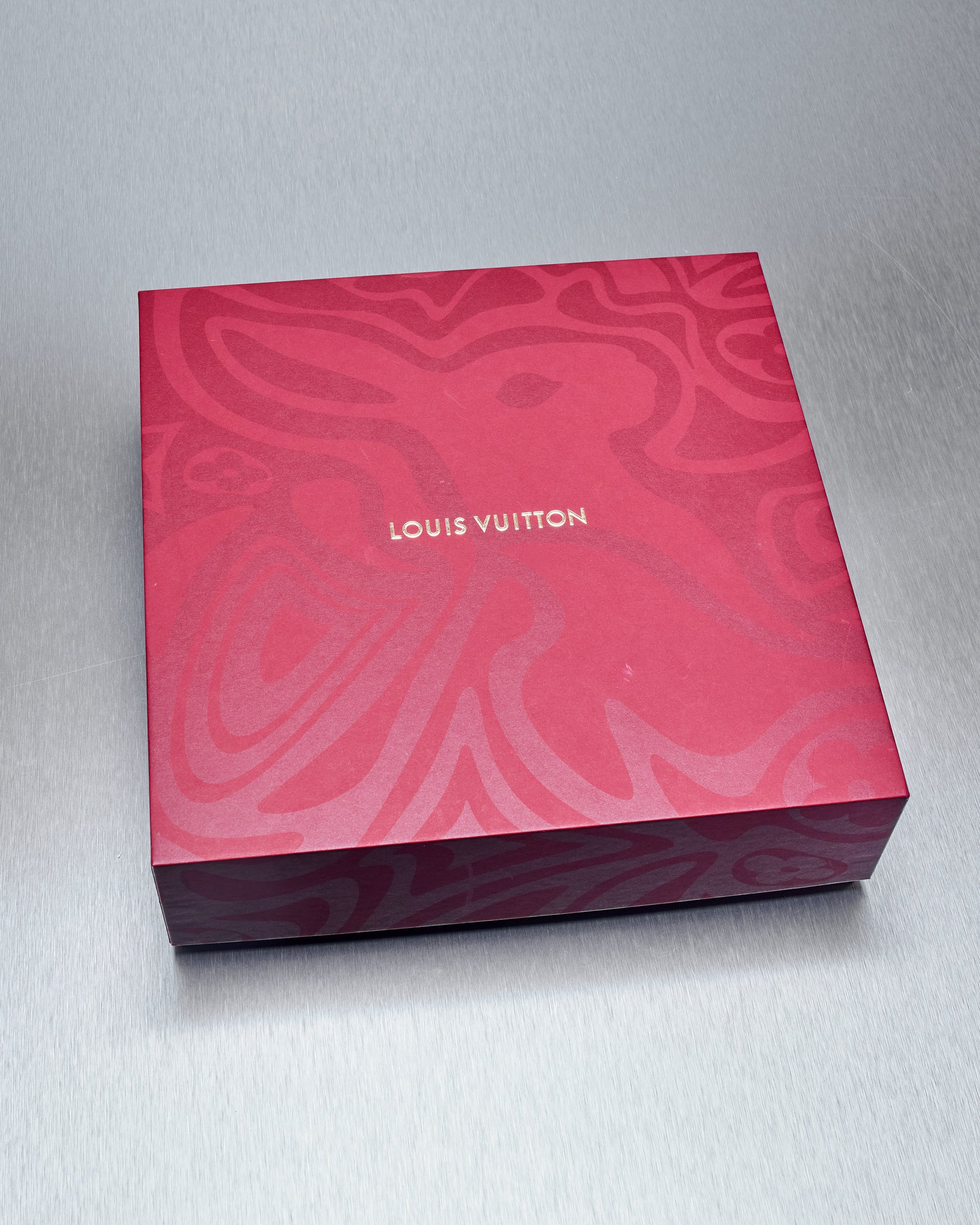 Louis Vuitton red box with intricate design on a gray background