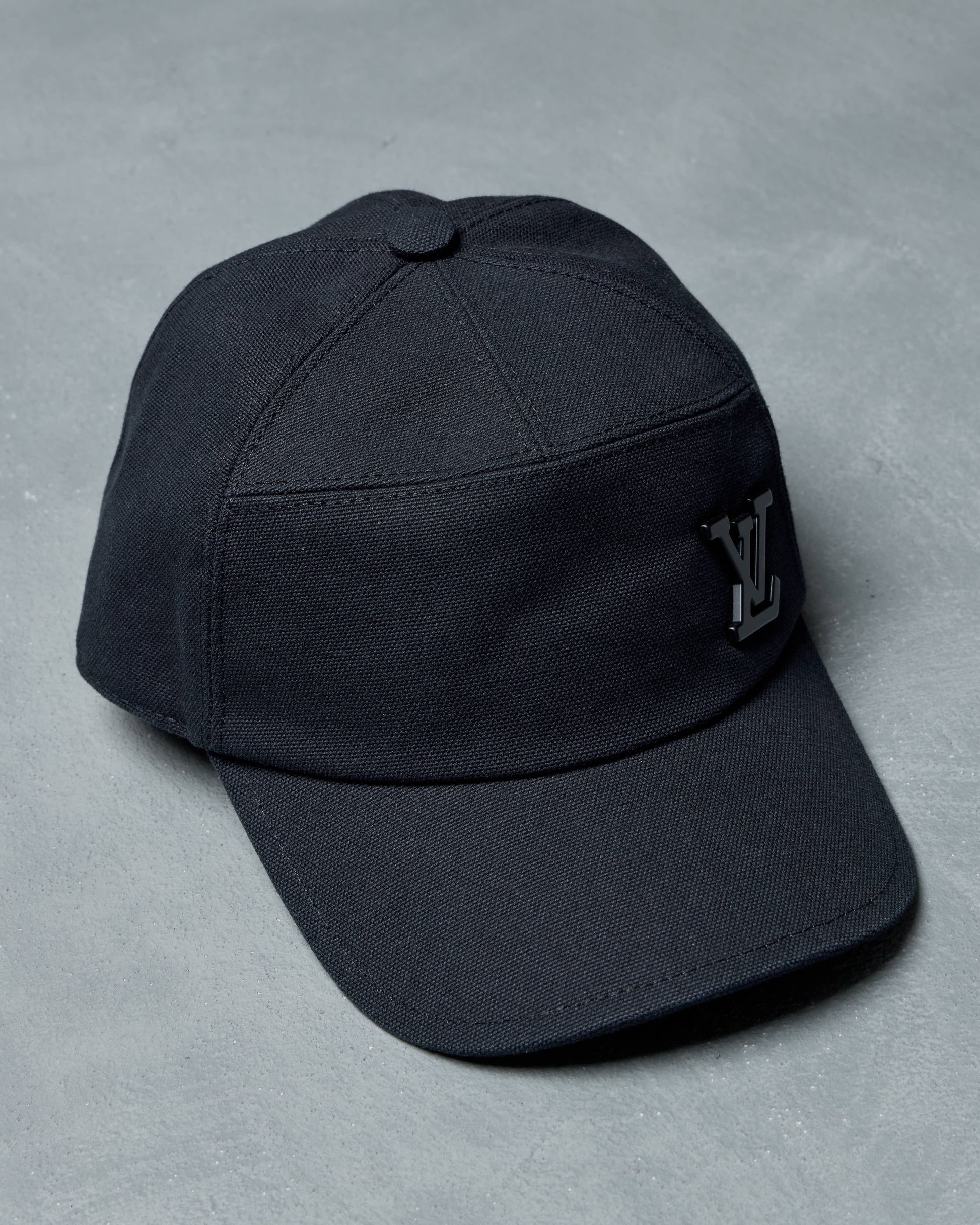 Black Louis Vuitton cap with a logo on a gray background
