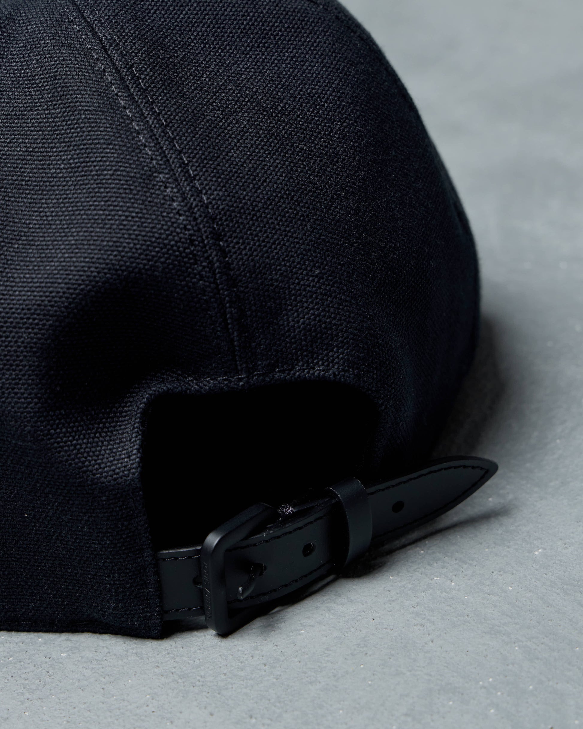 Black Louis Vuitton cap with a buckle on a gray surface