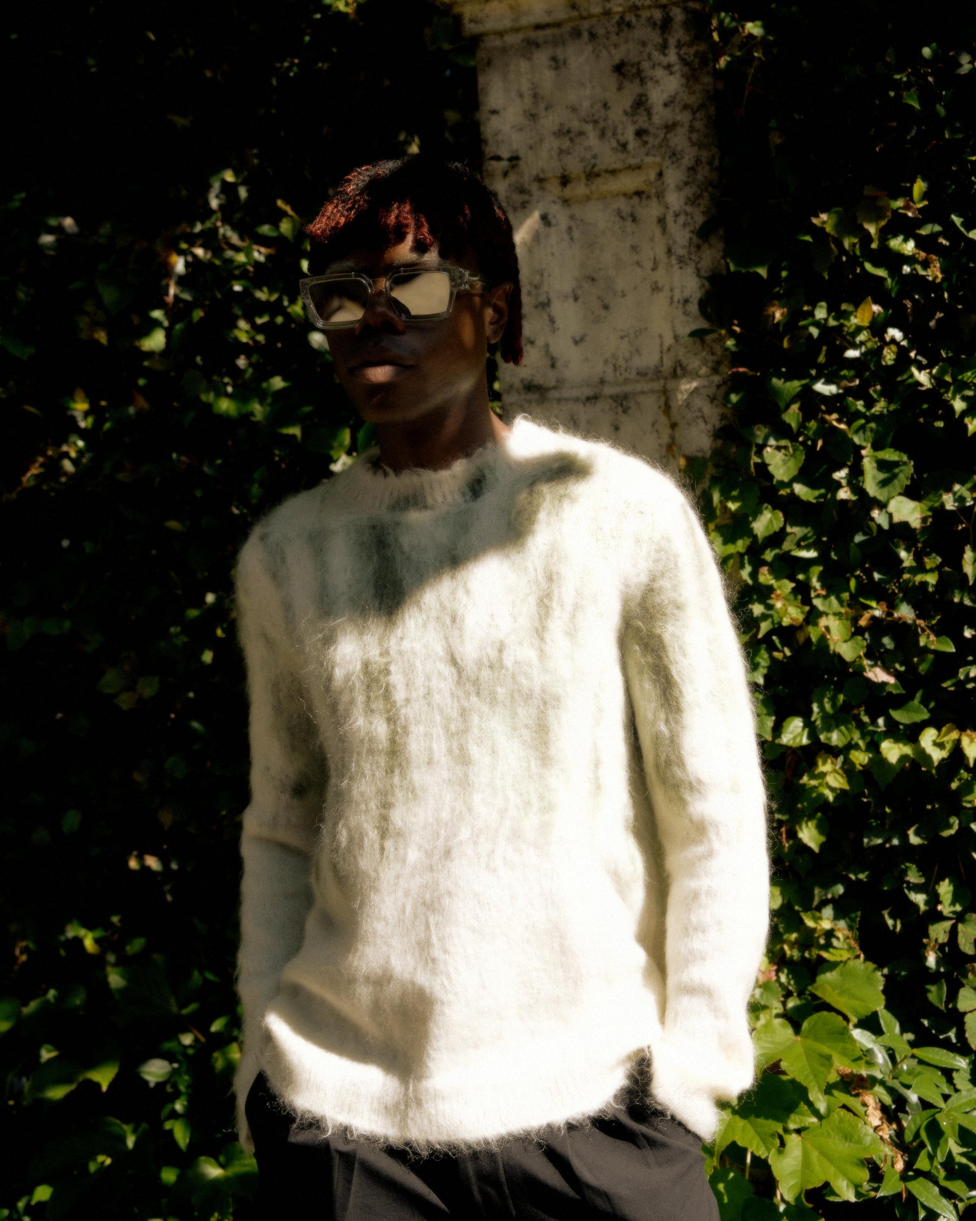 A person standing outdoors wearing sunglasses and a Louis Vuitton SS 2019 brushed intarsia mohair knit sweater in beige.